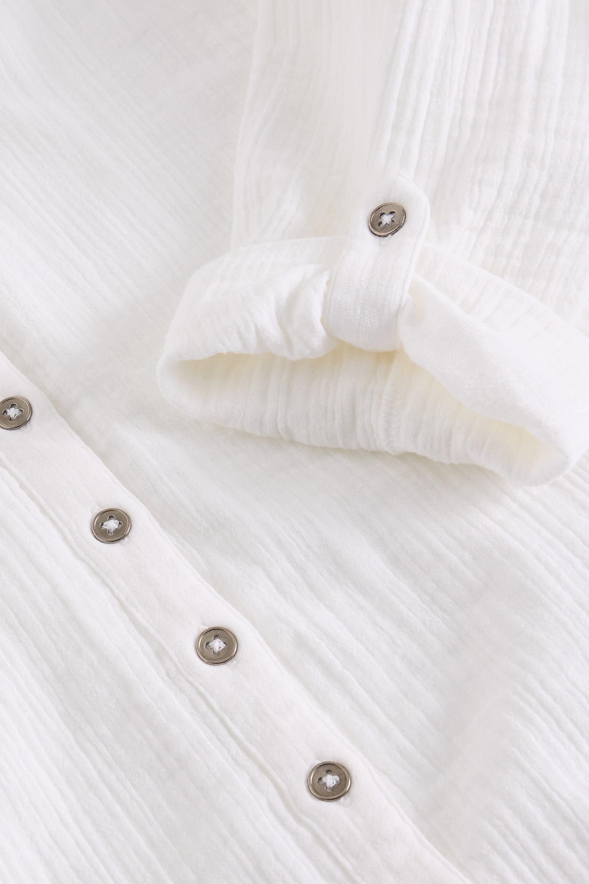 Close-up of a white organic cotton garment with button details