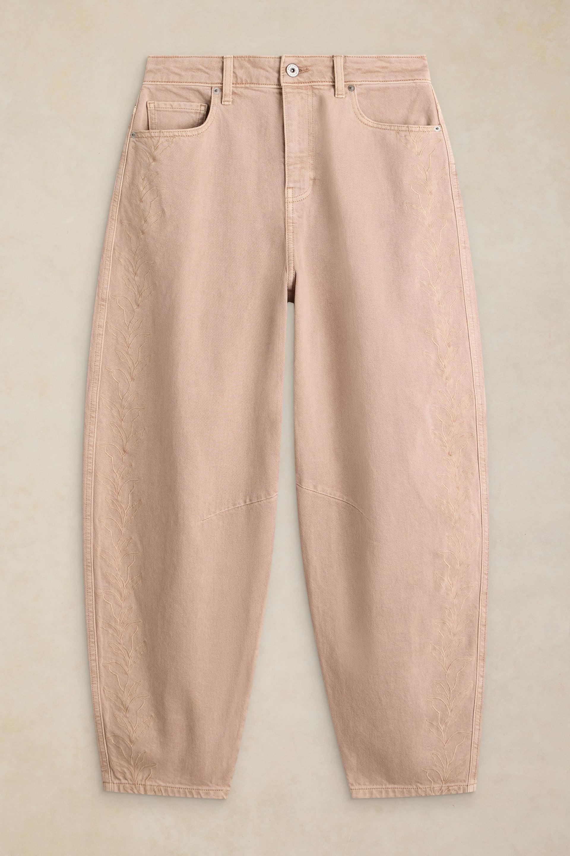 Beige organic cotton jeans with delicate leaf embroidery down the side seams on a neutral background.
