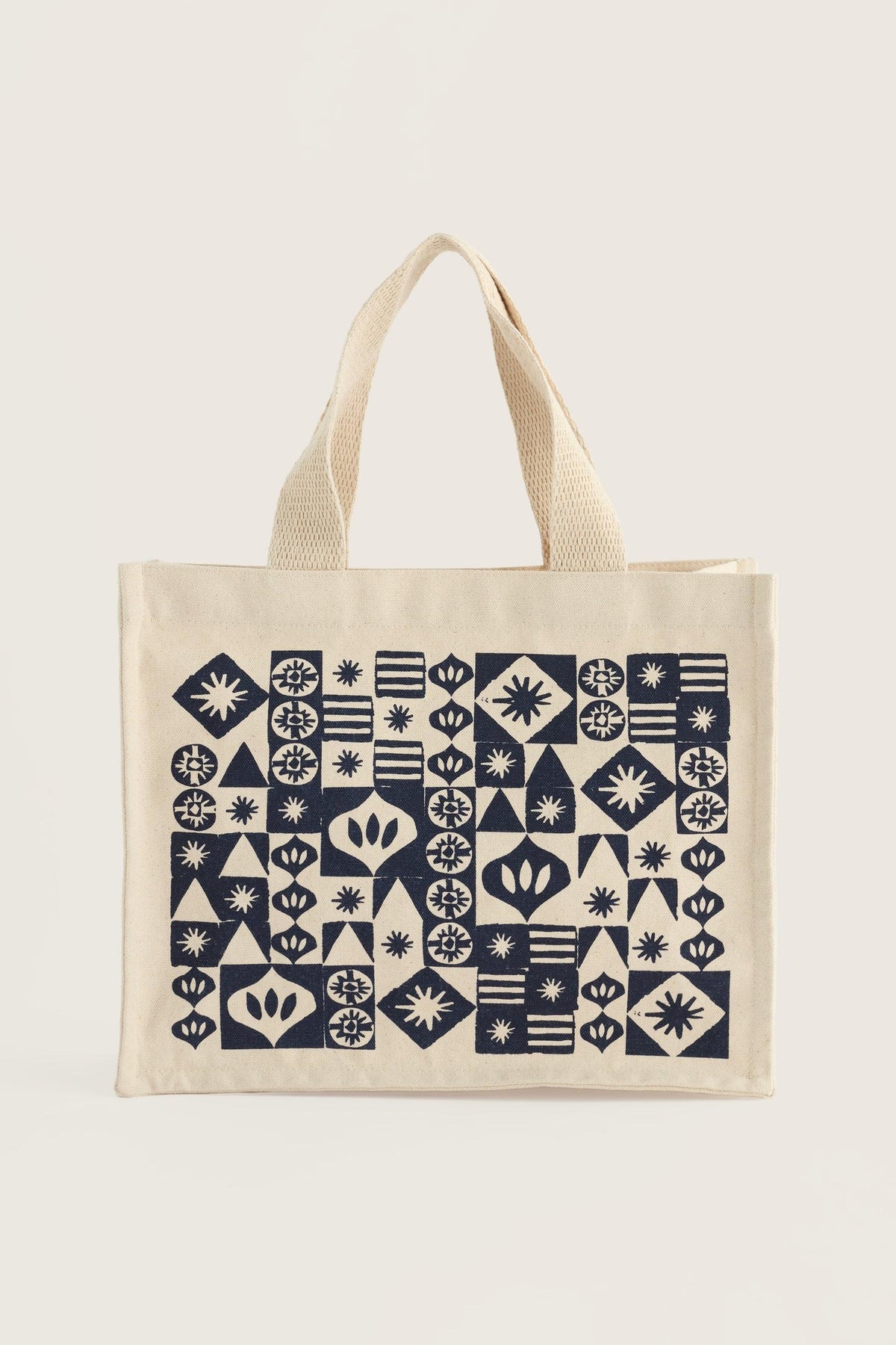 A reusable organic cotton canvas shopping bag with a dark blue geometric pattern on a light background.