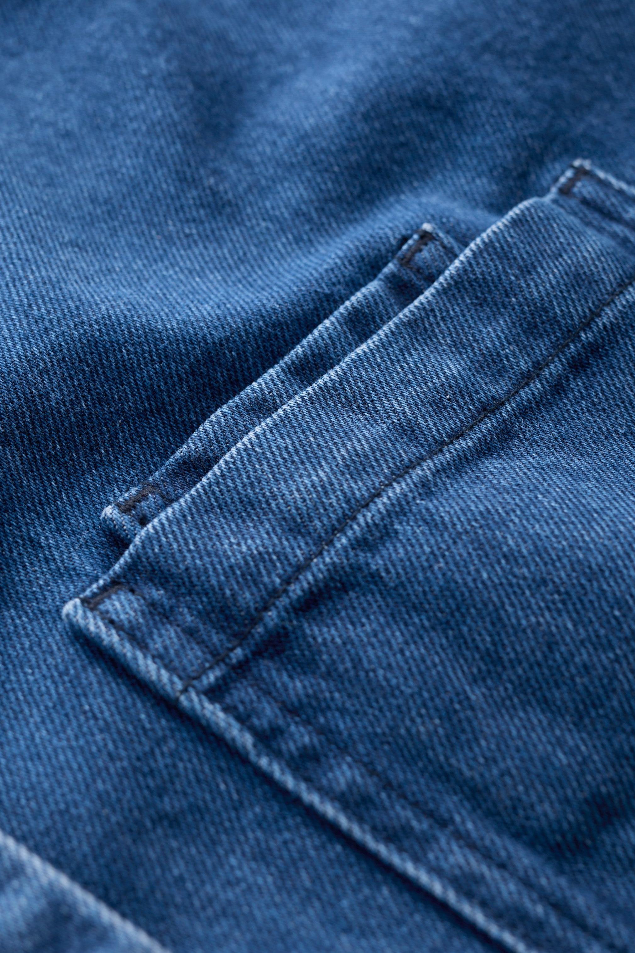 Close-up of blue denim fabric with a focus on texture and stitching.