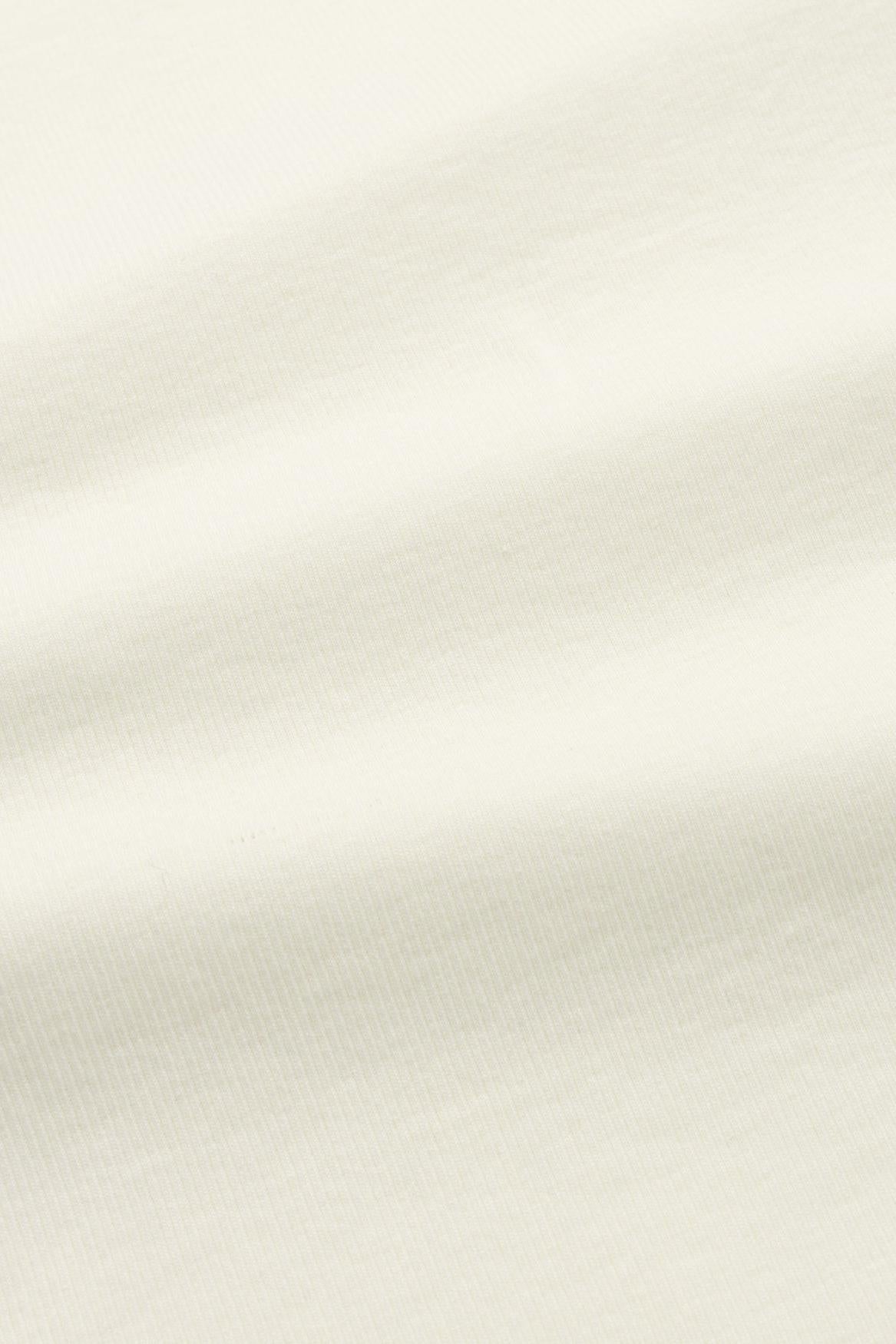 A close-up of a soft, light cream fabric with subtle folds and a fine knit texture.