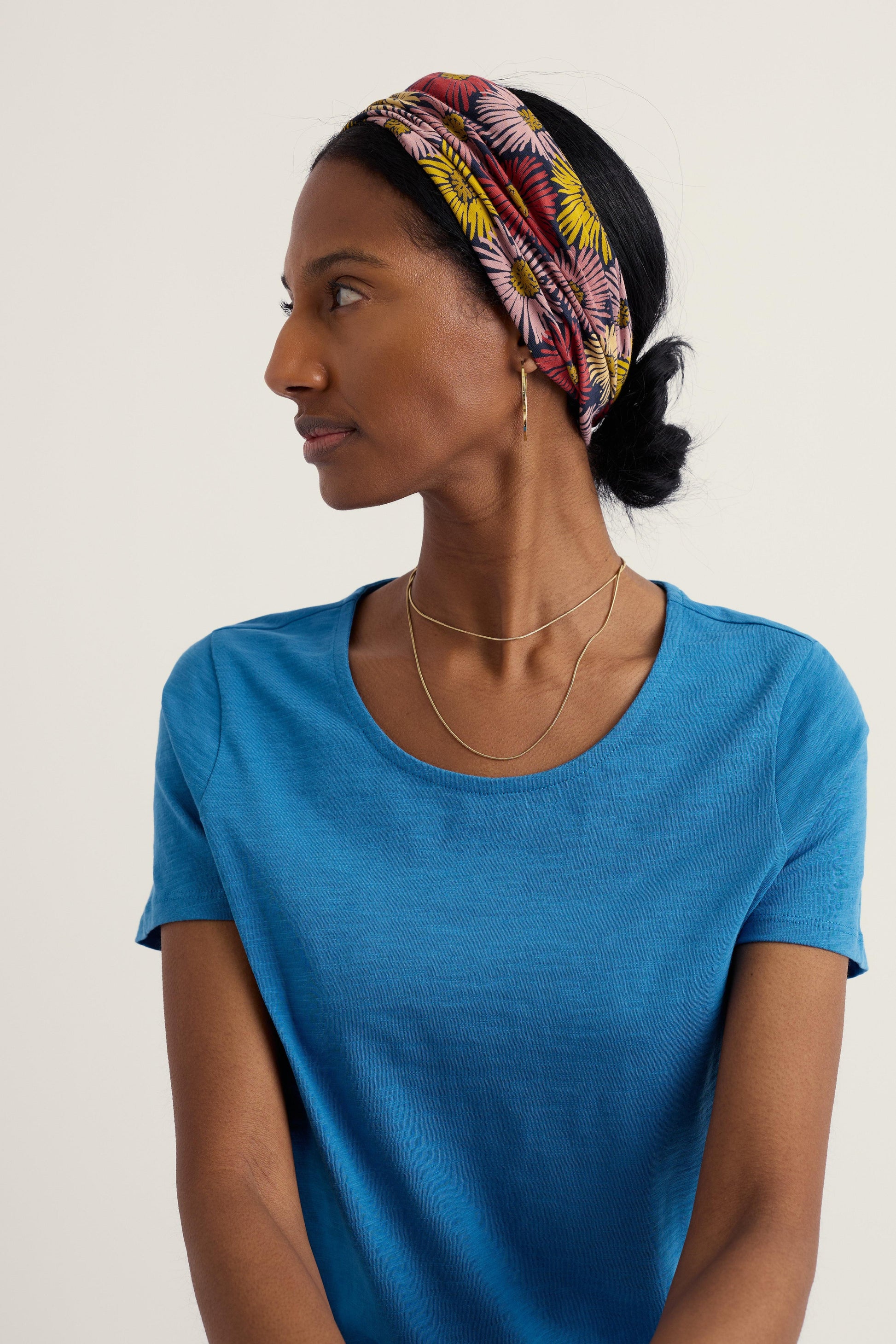 Woman wearing a colorful headband and blue shirt against a plain background