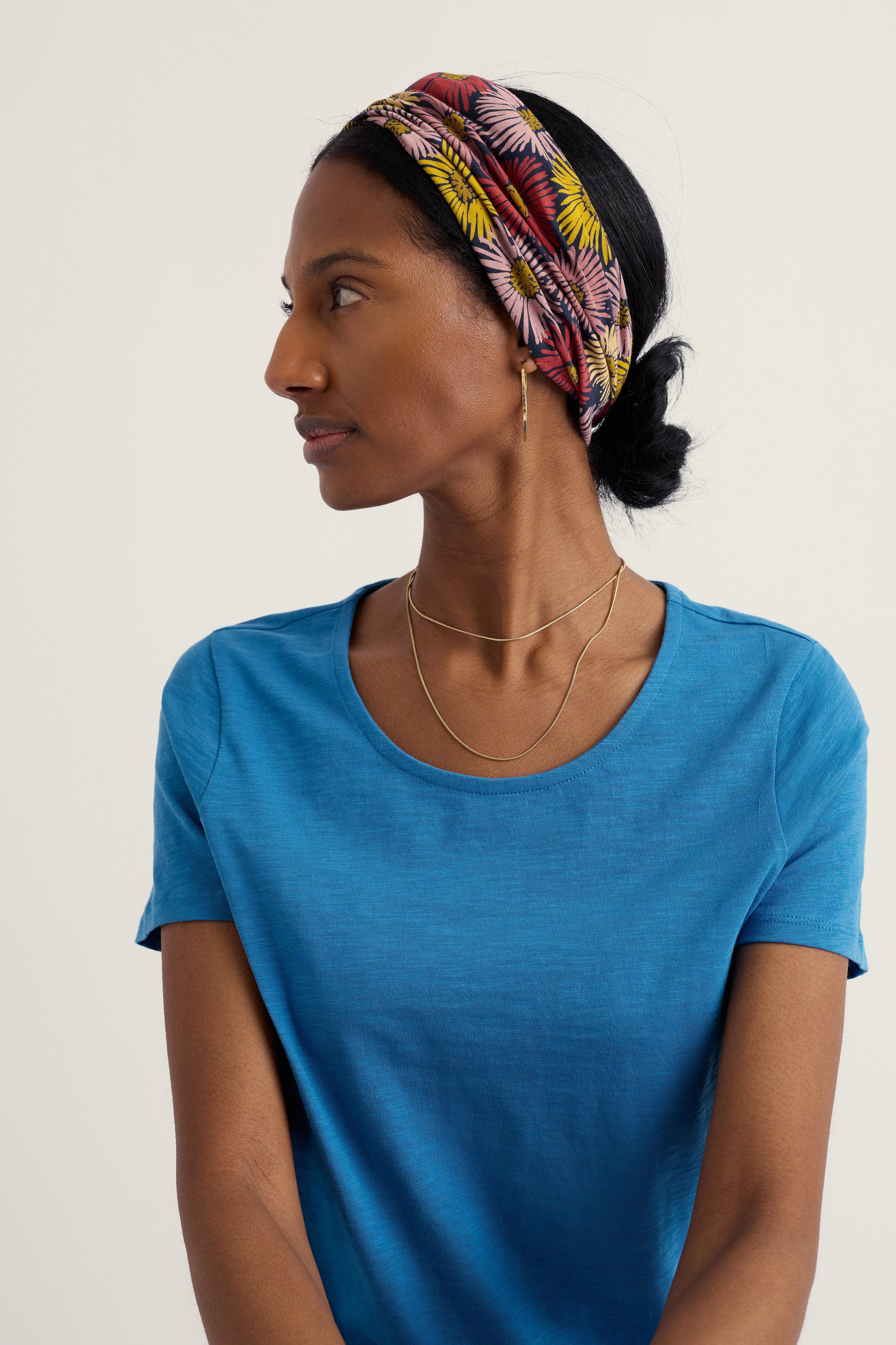 Woman wearing a colorful headband and blue shirt against a plain background