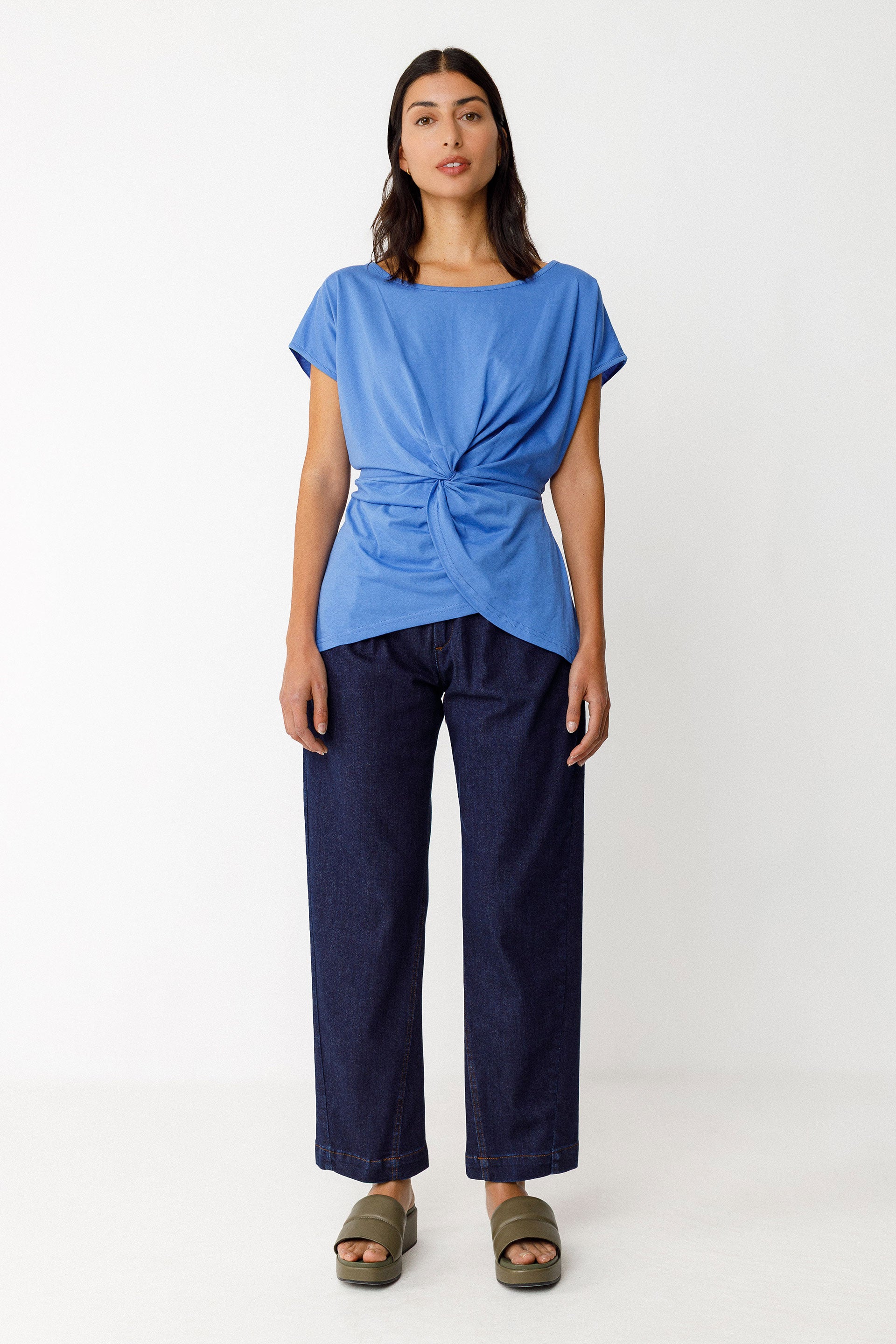Woman wearing a blue top and blue jeans on a white background