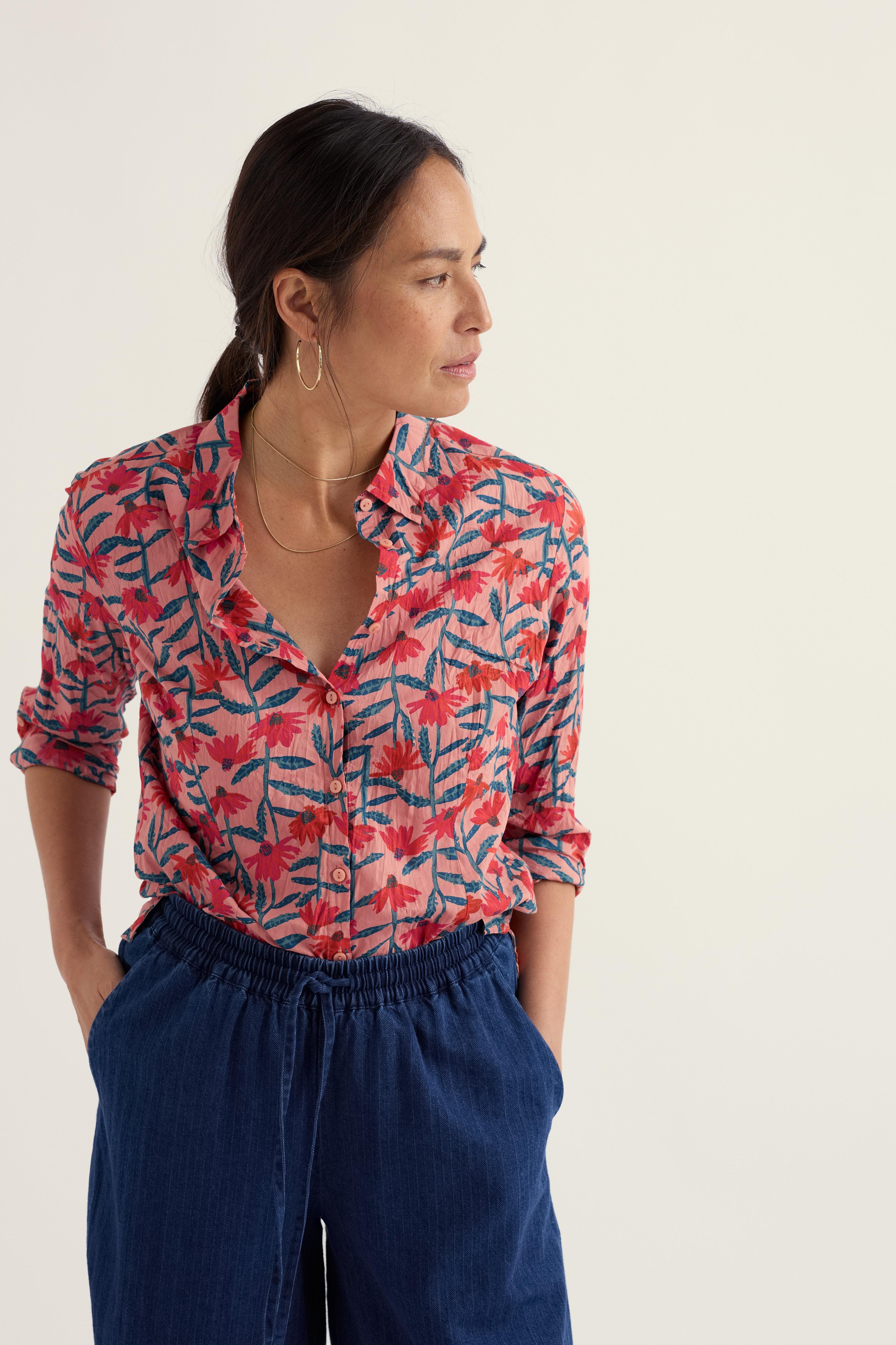 Woman wearing a colourful floral shirt and navy pants on a white background