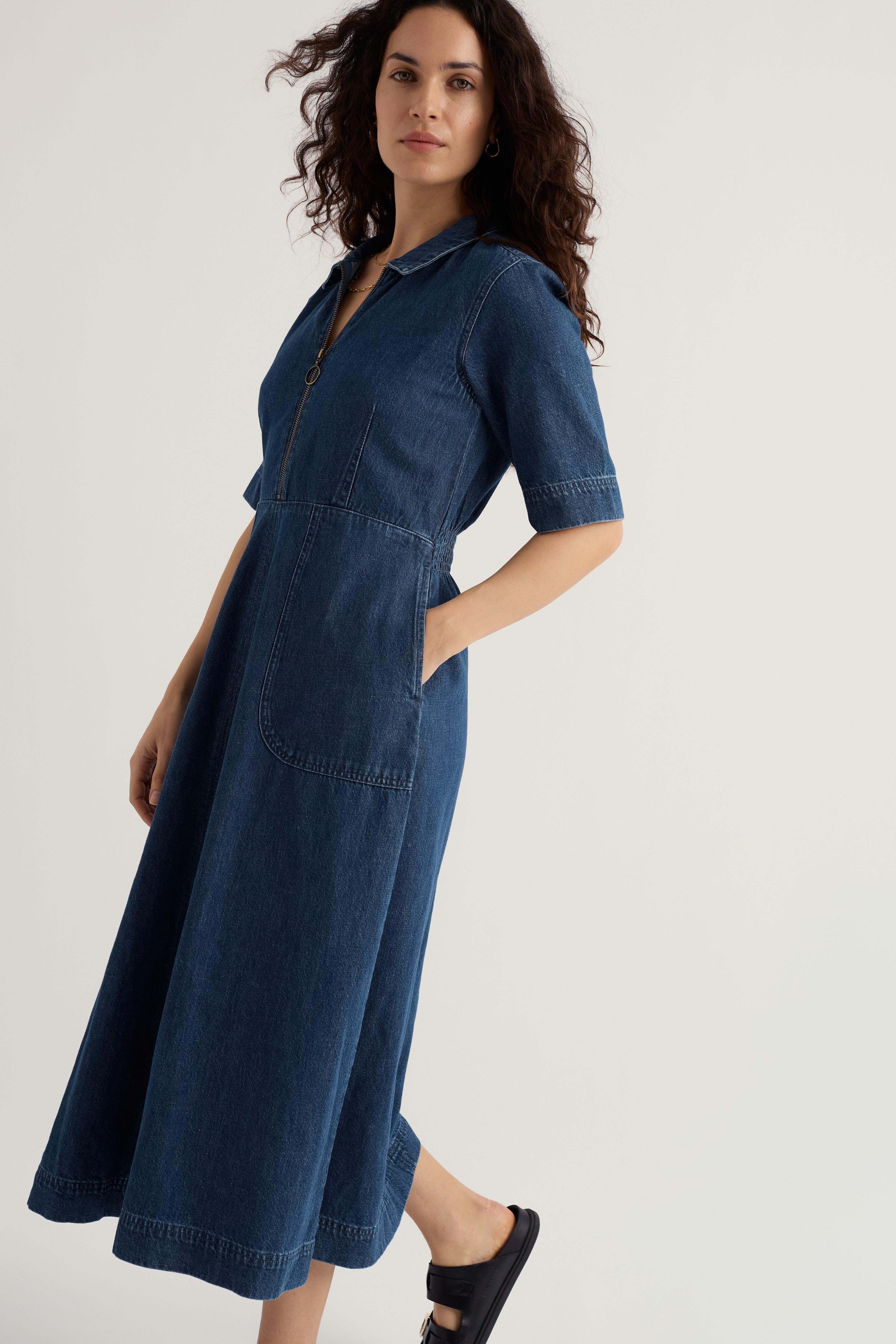 Woman wearing a blue denim dress on a light gray background
