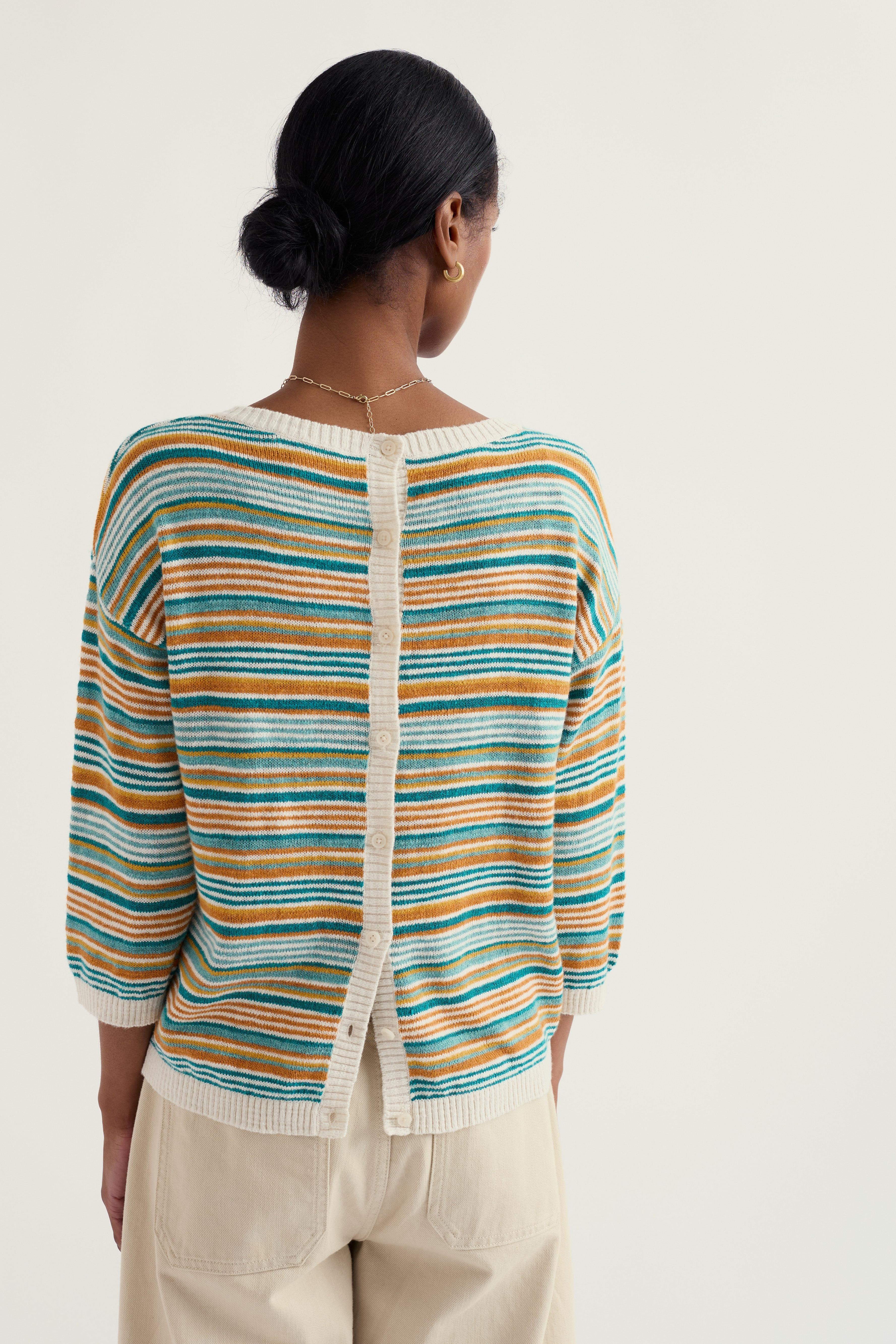 Woman wearing a striped Seasalt sweater with a plain background