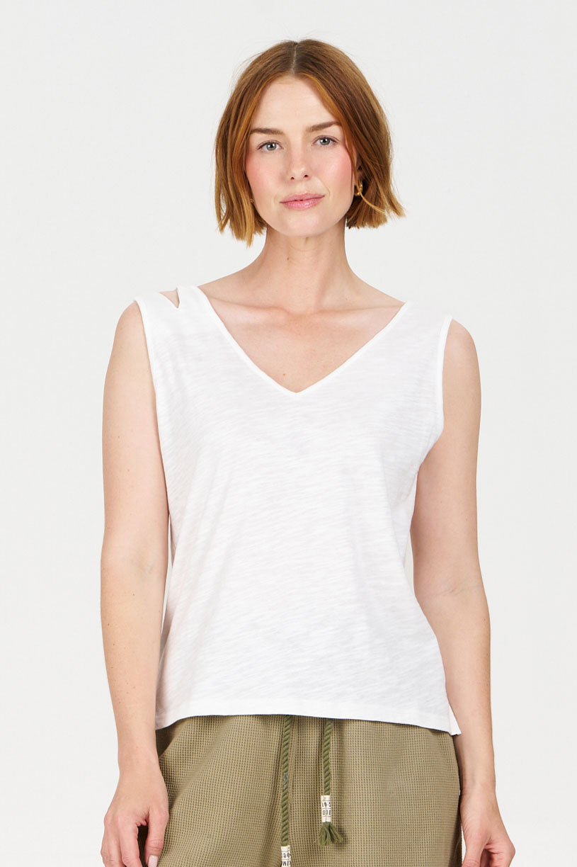 Woman wearing a white sleeveless top on a plain background