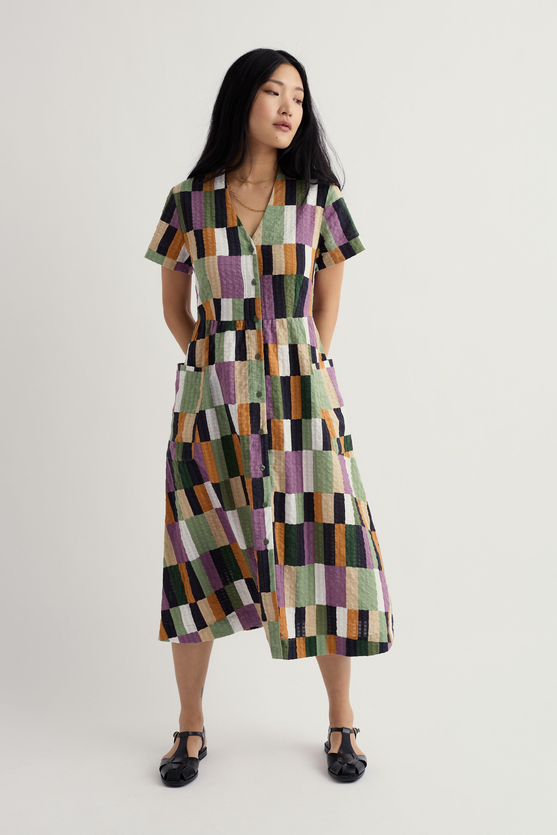 Woman wearing a patterned organic cotton dress on a plain background