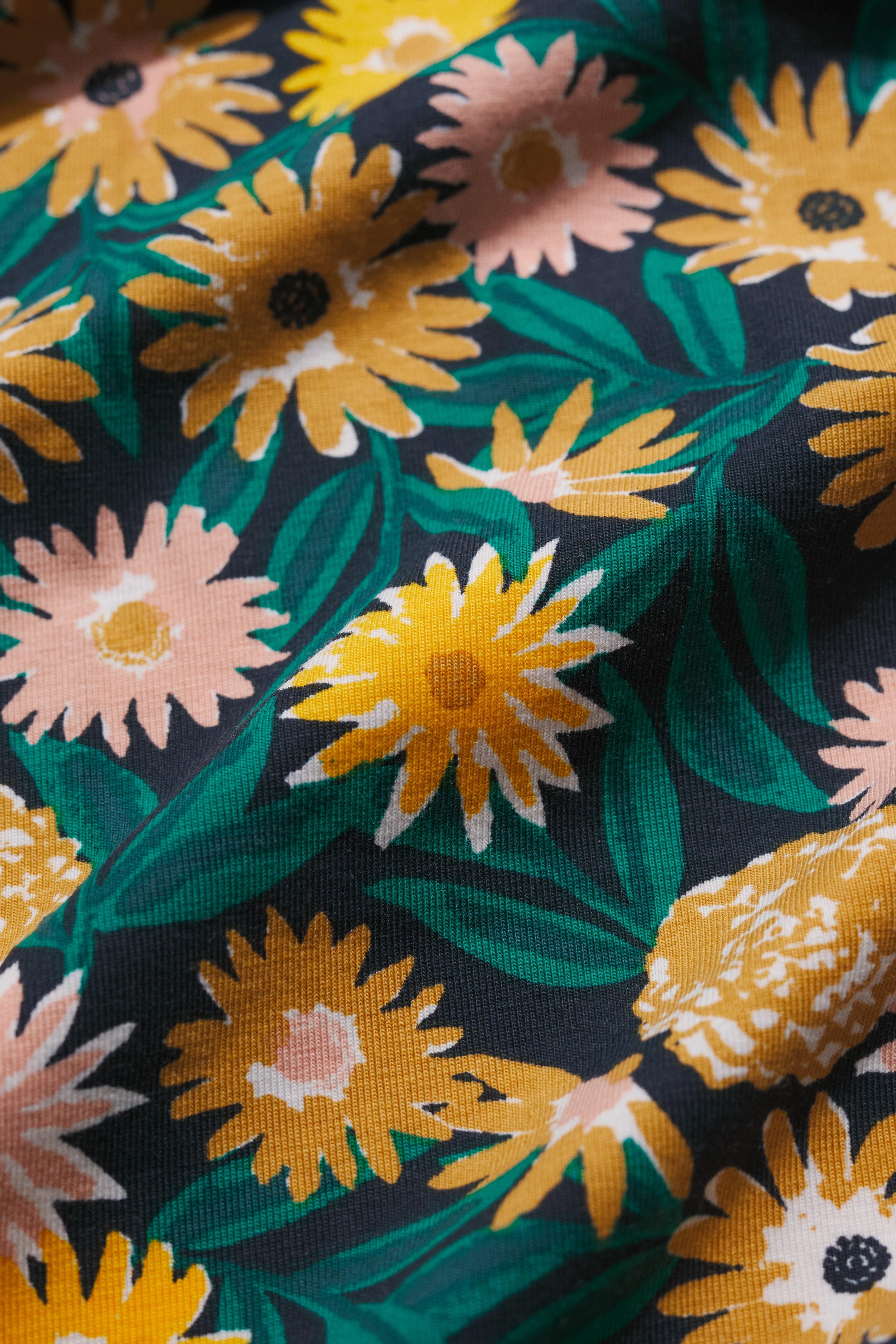 Close-up of floral fabric with yellow and pink flowers on a dark background