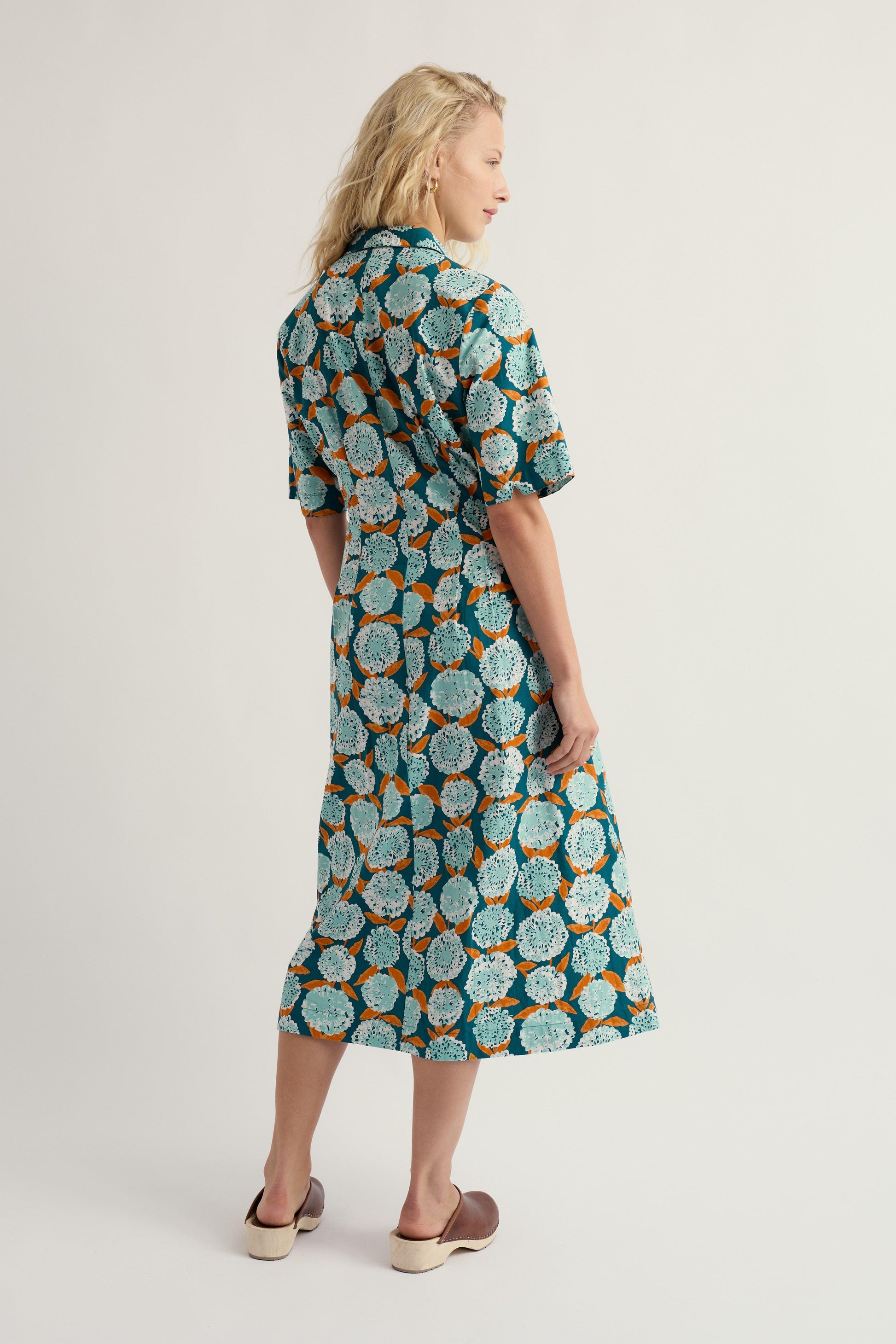 Woman wearing a patterned organic cotton dress on a plain background