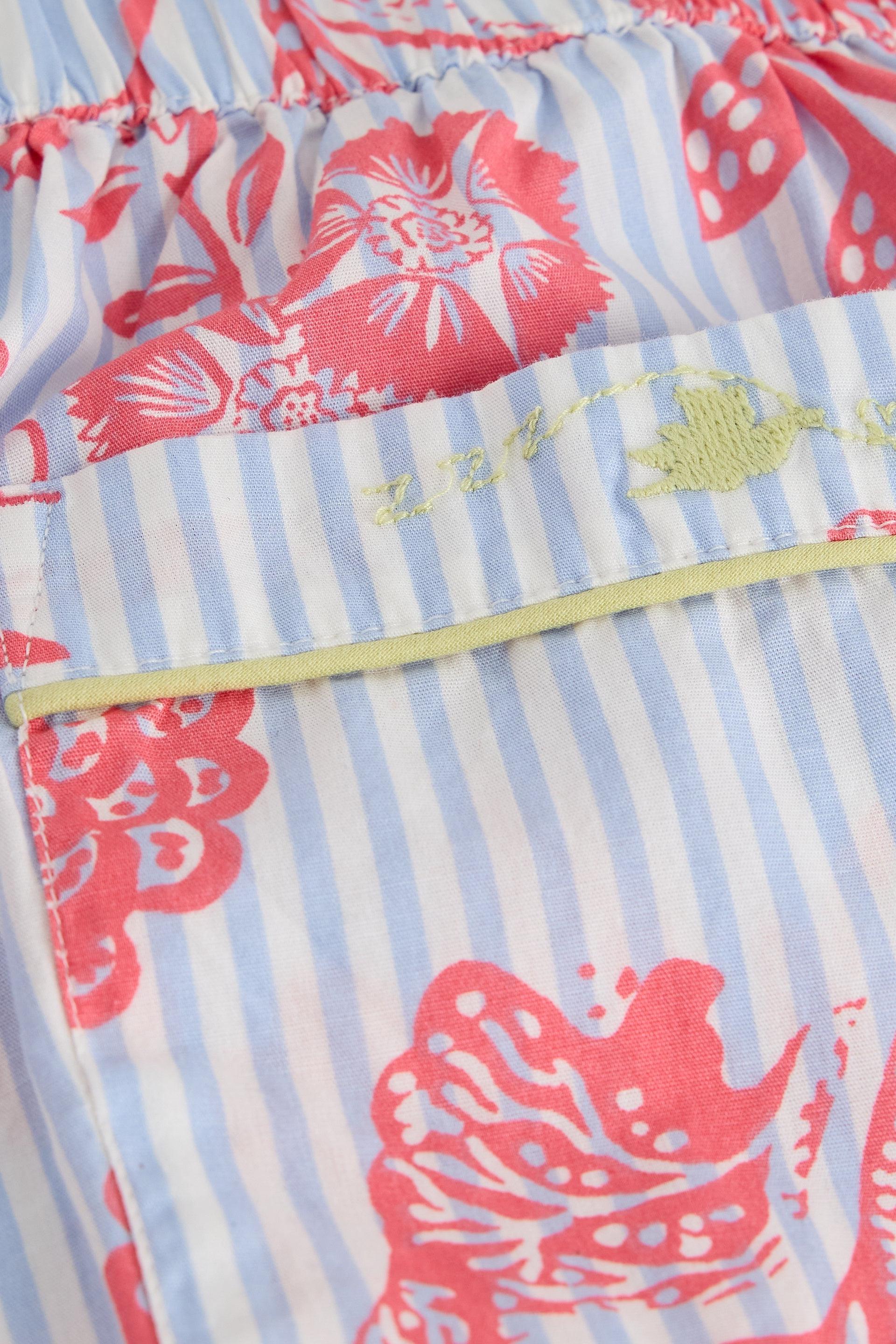 Close-up of organic cotton pyjamas with a blue stripe and pink floral print featuring an embroidered pocket.