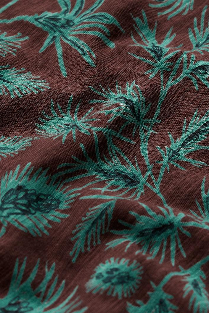 Close-up of Seasalt Cornwall organic cotton fabric featuring a brown background with blue-green botanical thistle print.
