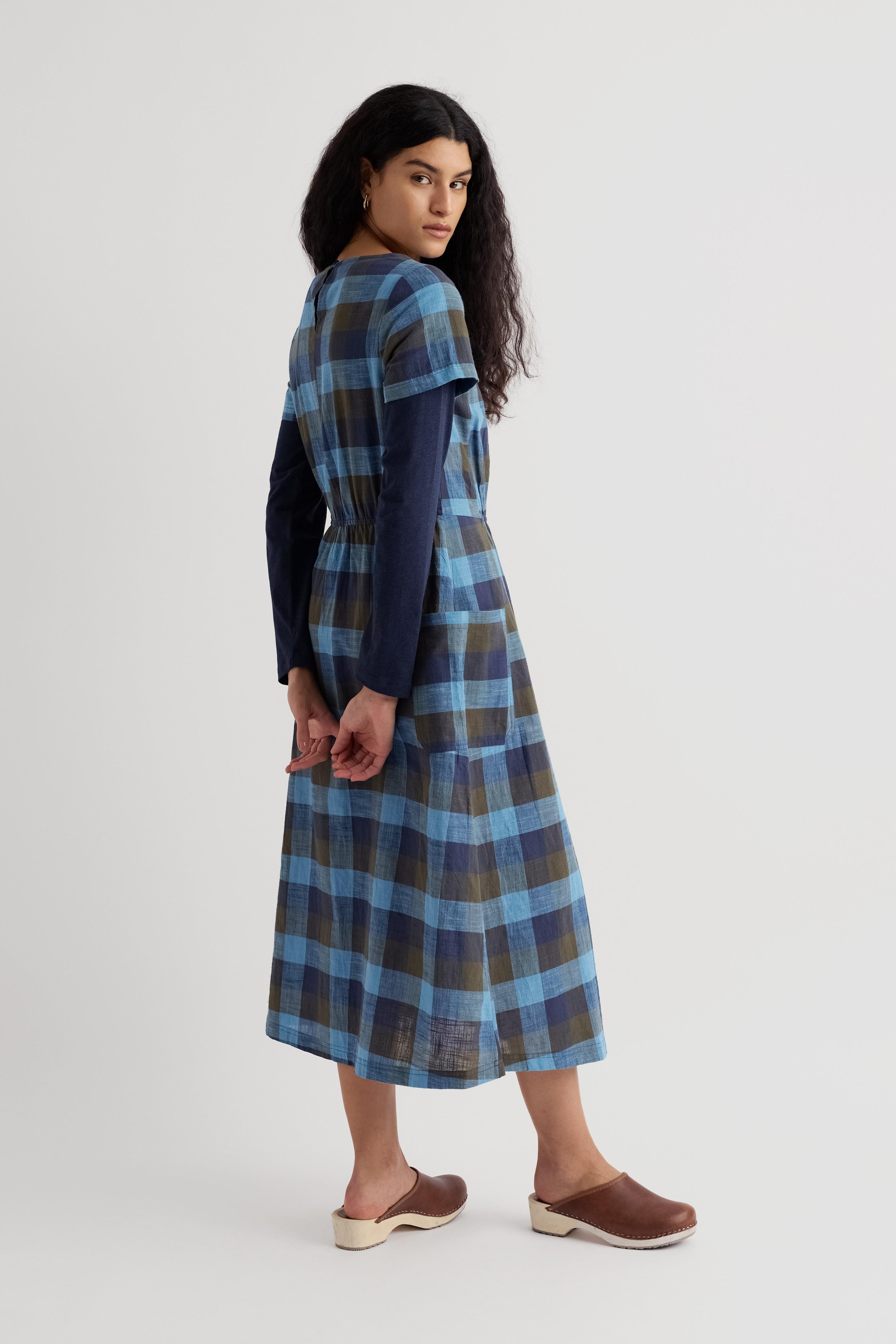 Woman wearing a blue plaid organic cotton dress on a white background