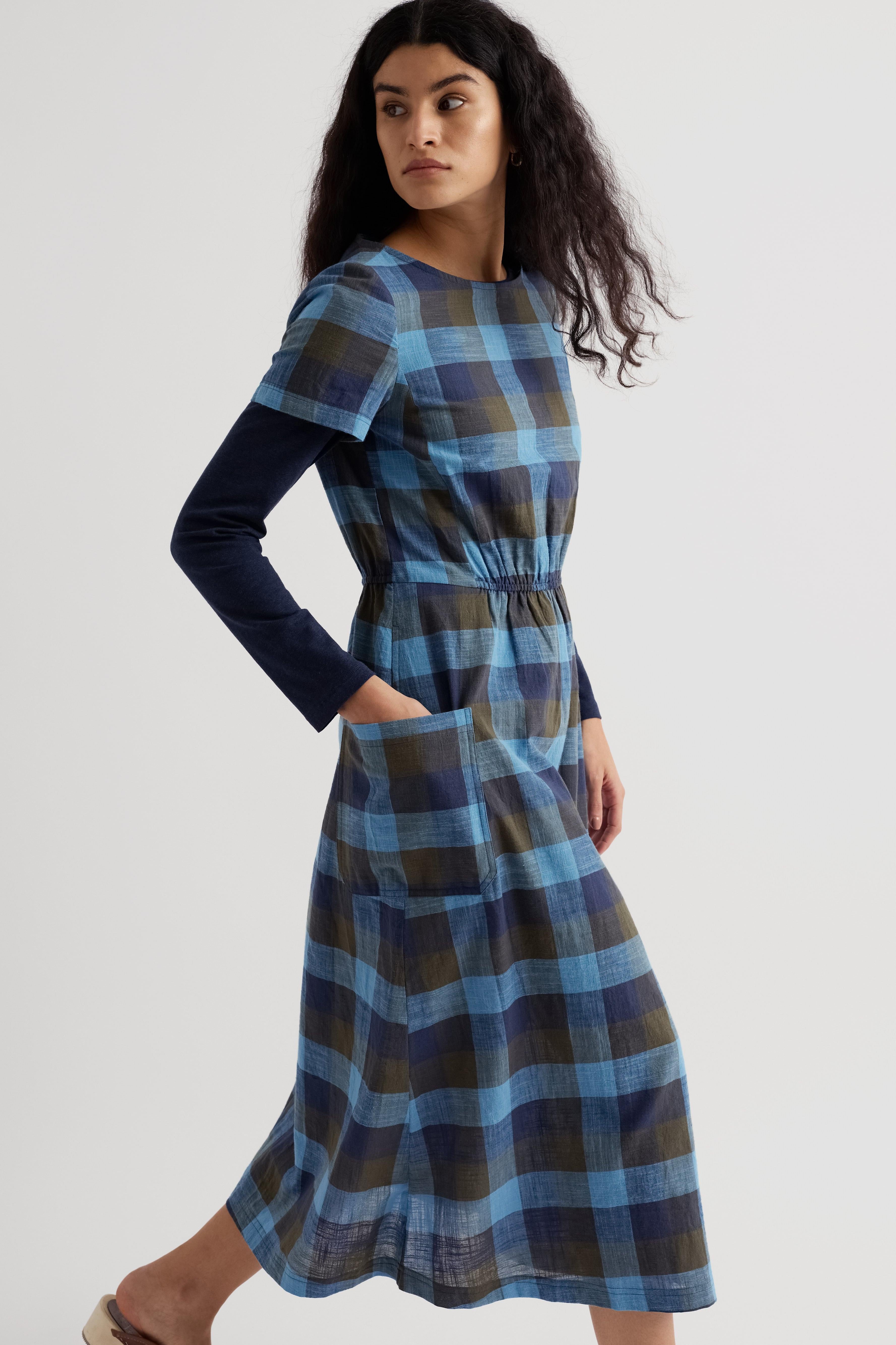 Woman wearing a blue and green plaid dress on a white background