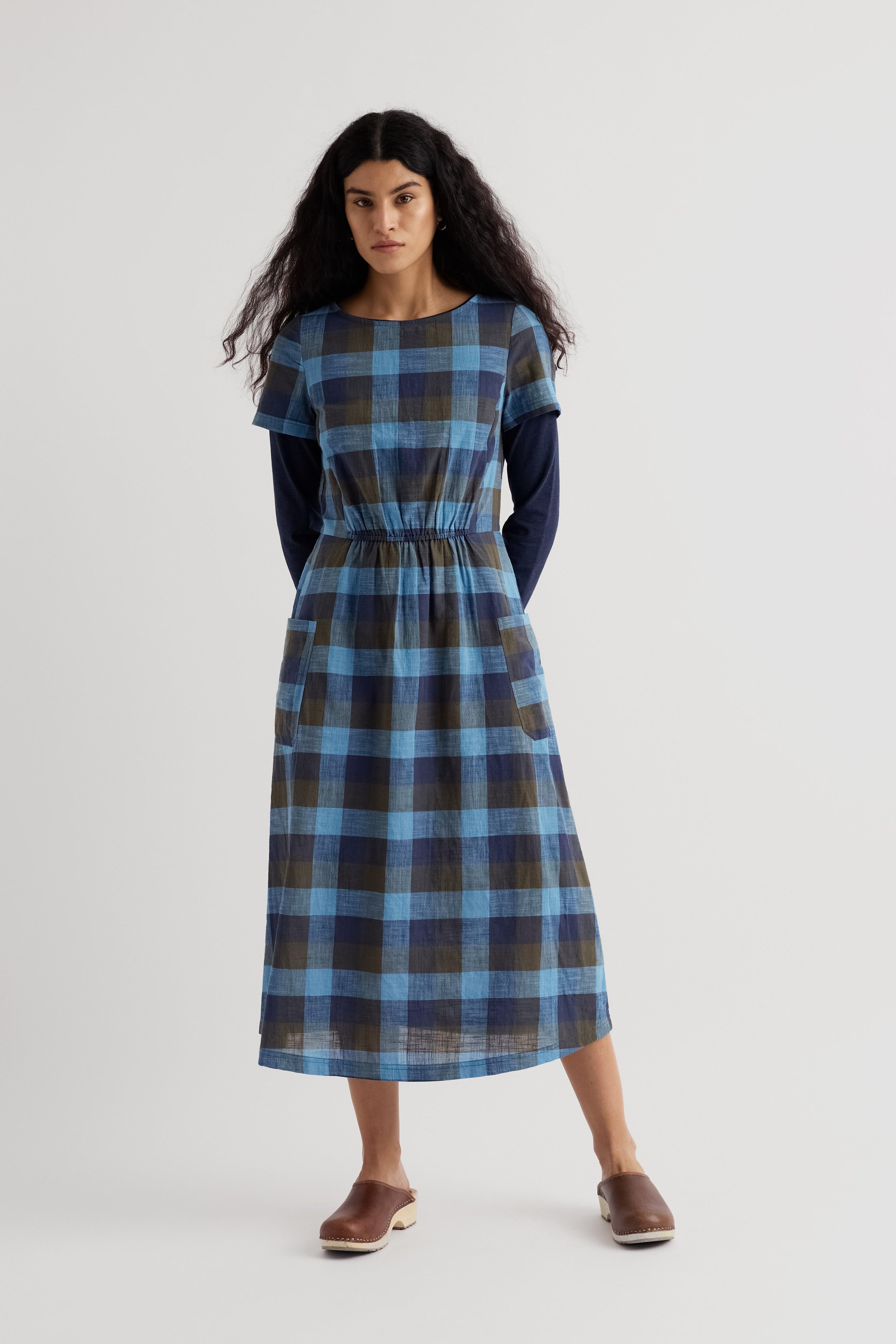 Woman wearing a blue and black plaid waisted dress on a white background