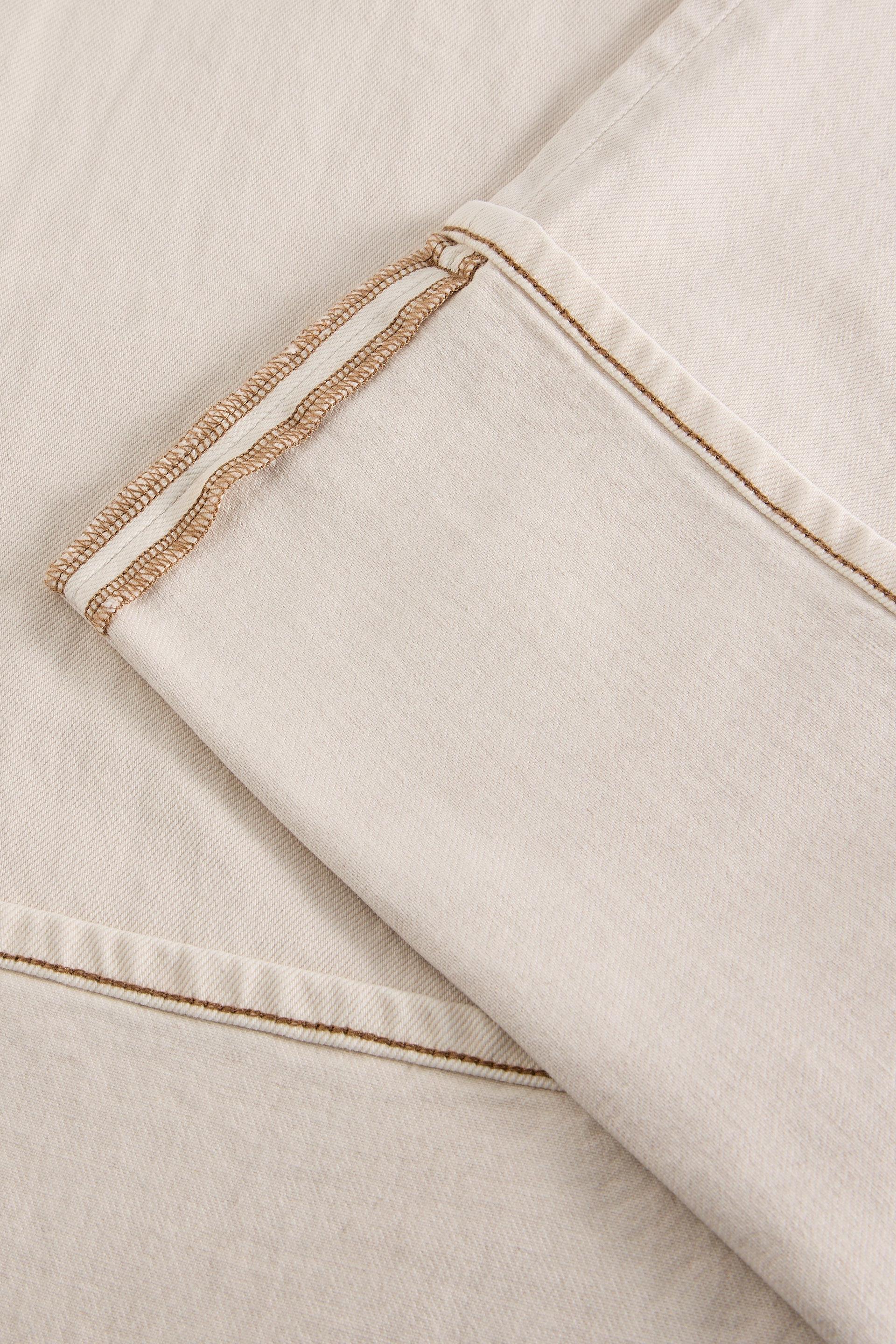 Close up of a cream organic cotton trouser hem with brown stitched seam details from White Stuff.