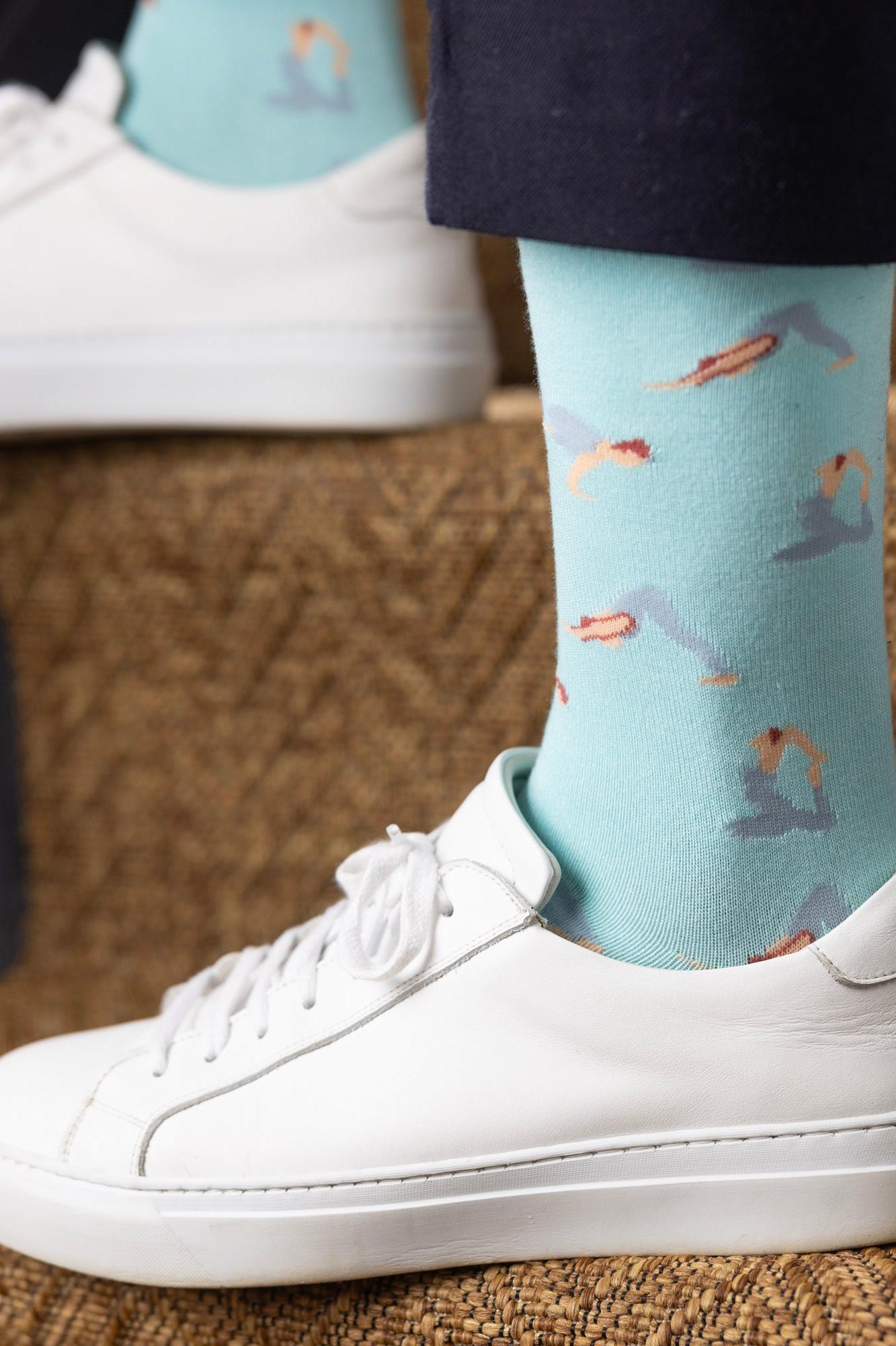 Person wearing light blue yoga theme bamboo socks with white sneakers on stairs