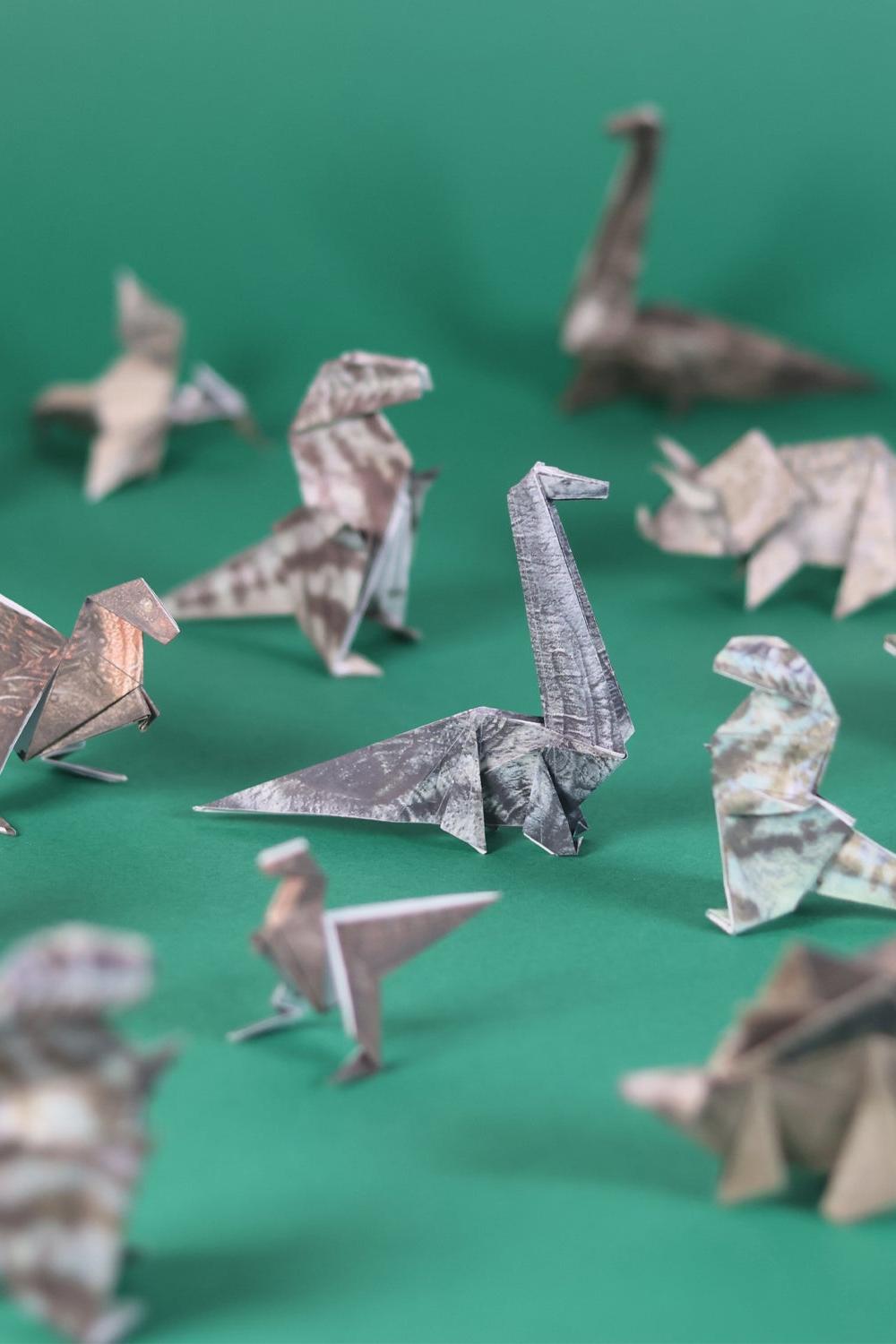 Collection of origami dinosaurs on a green background