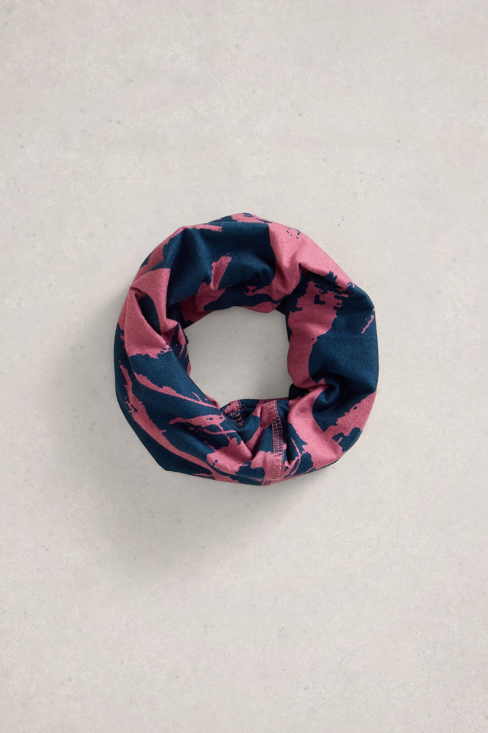 A pink and navy blue patterned neck gaiter circular scarf on a light gray background
