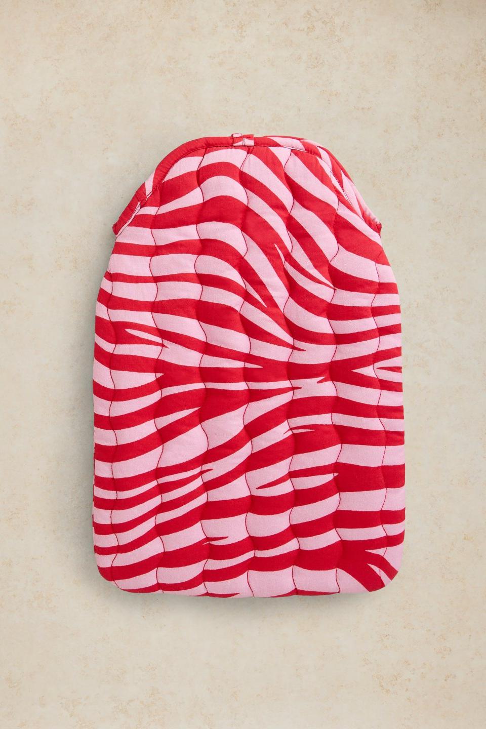 A quilted cotton hot water bottle cover in a fun red and pink animal print.