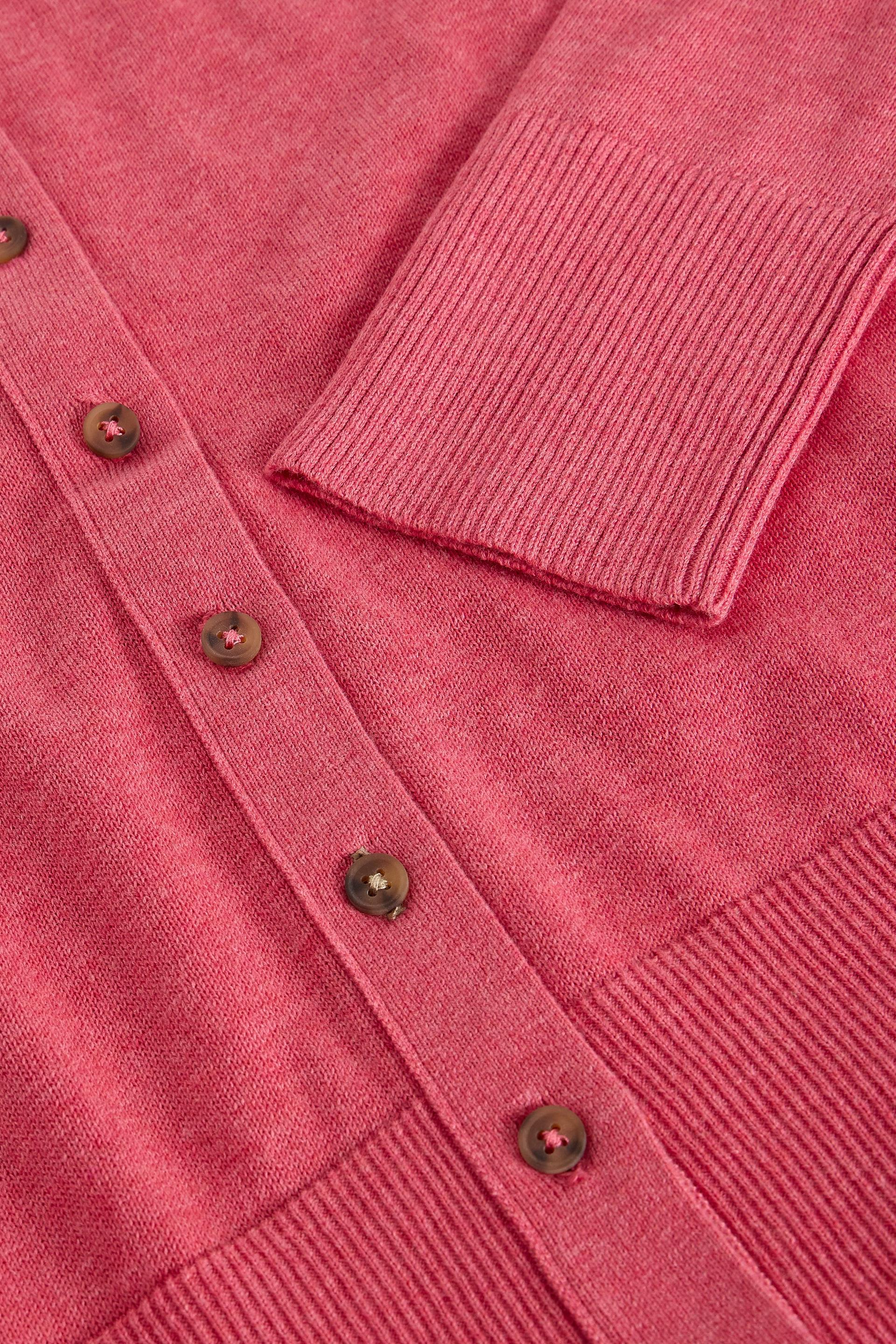 Close-up of a pink button-down cardigan sweater made from organic cotton fabric with visible ribbed cuffs