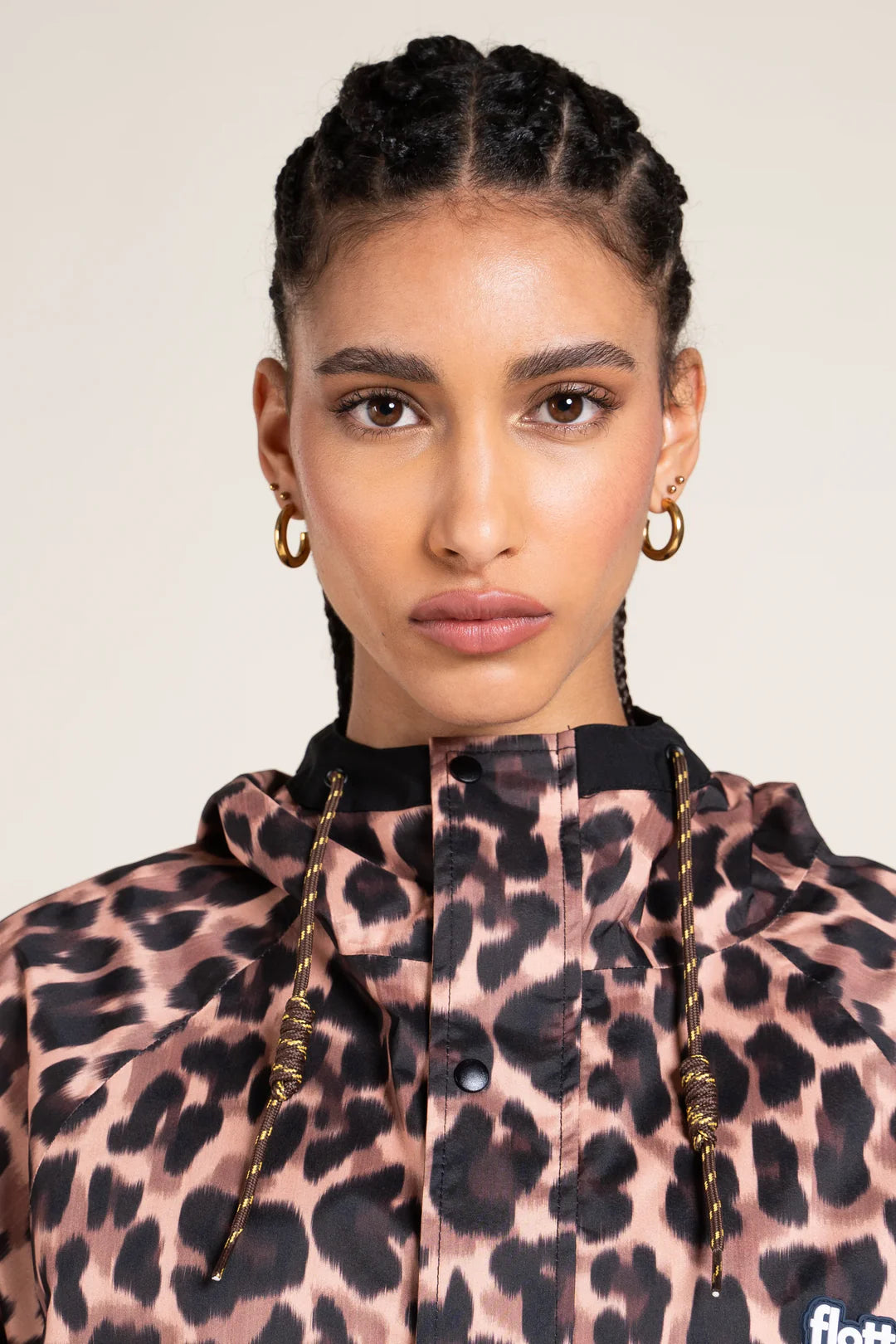 Woman wearing a leopard print jacket with braided hair against a plain background