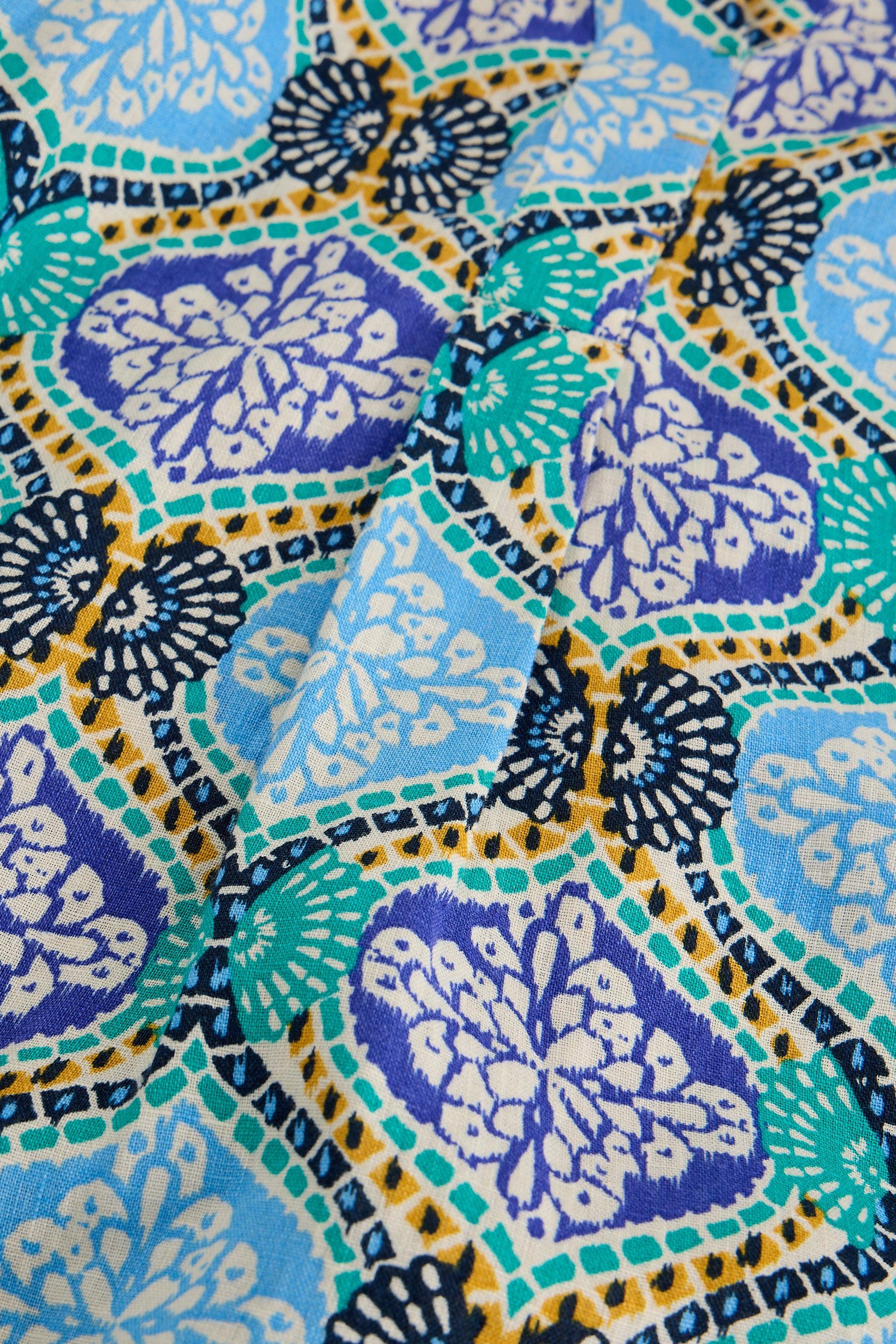 Close-up of linen fabric with a colourful pattern featuring blue, green, and purple colors.