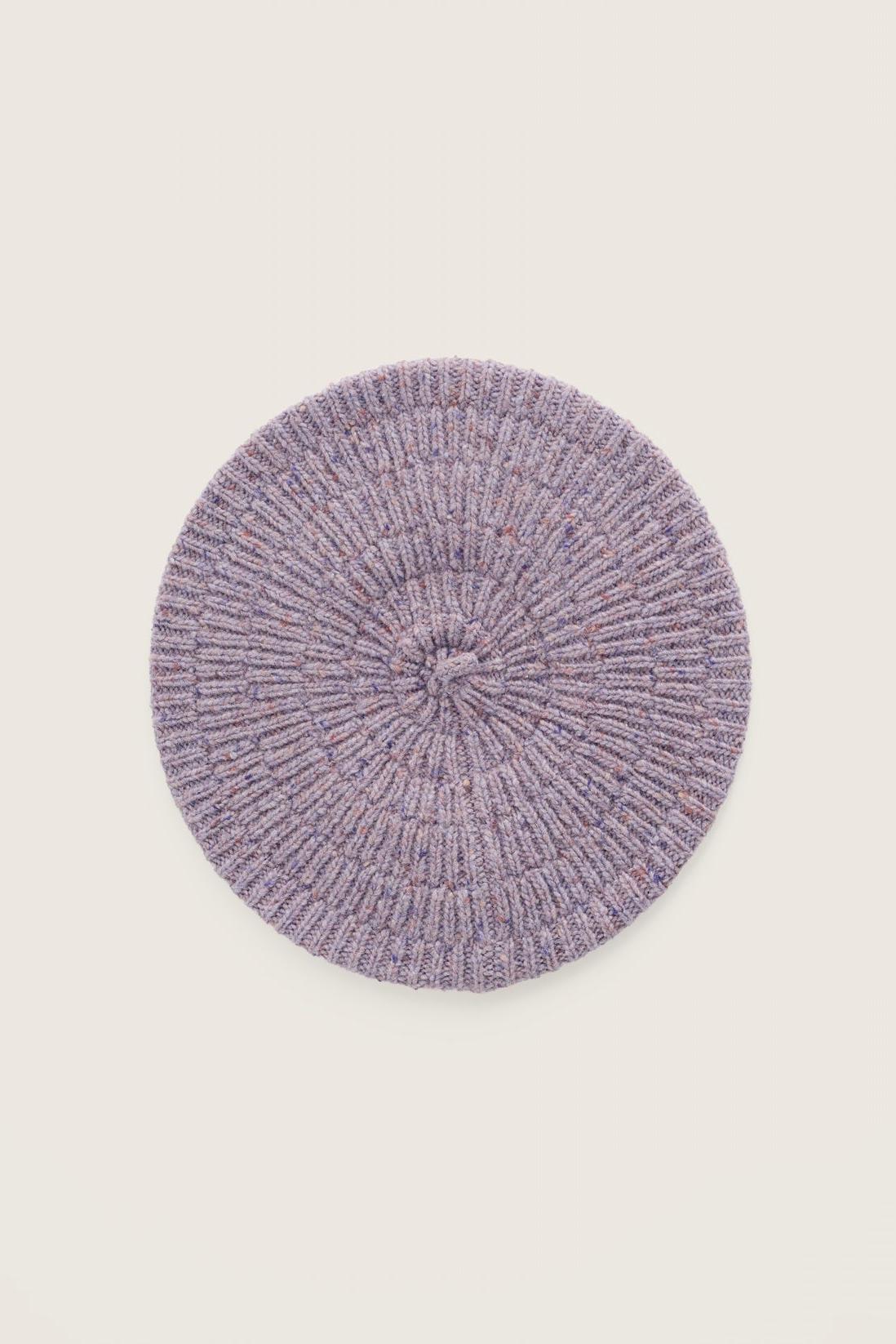 A top-down view of a textured purple merino wool beret hat against a neutral background.