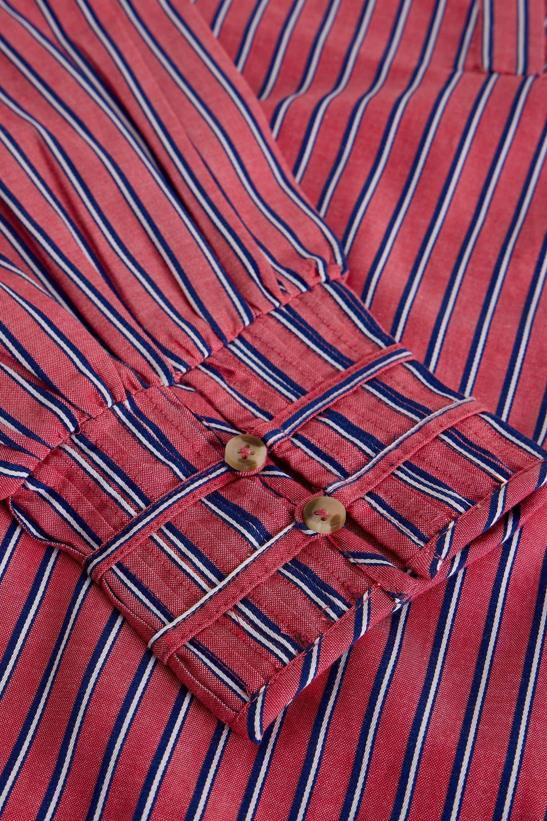 Close-up of a pink striped shirt with navy and white vertical stripes, featuring a buttoned cuff