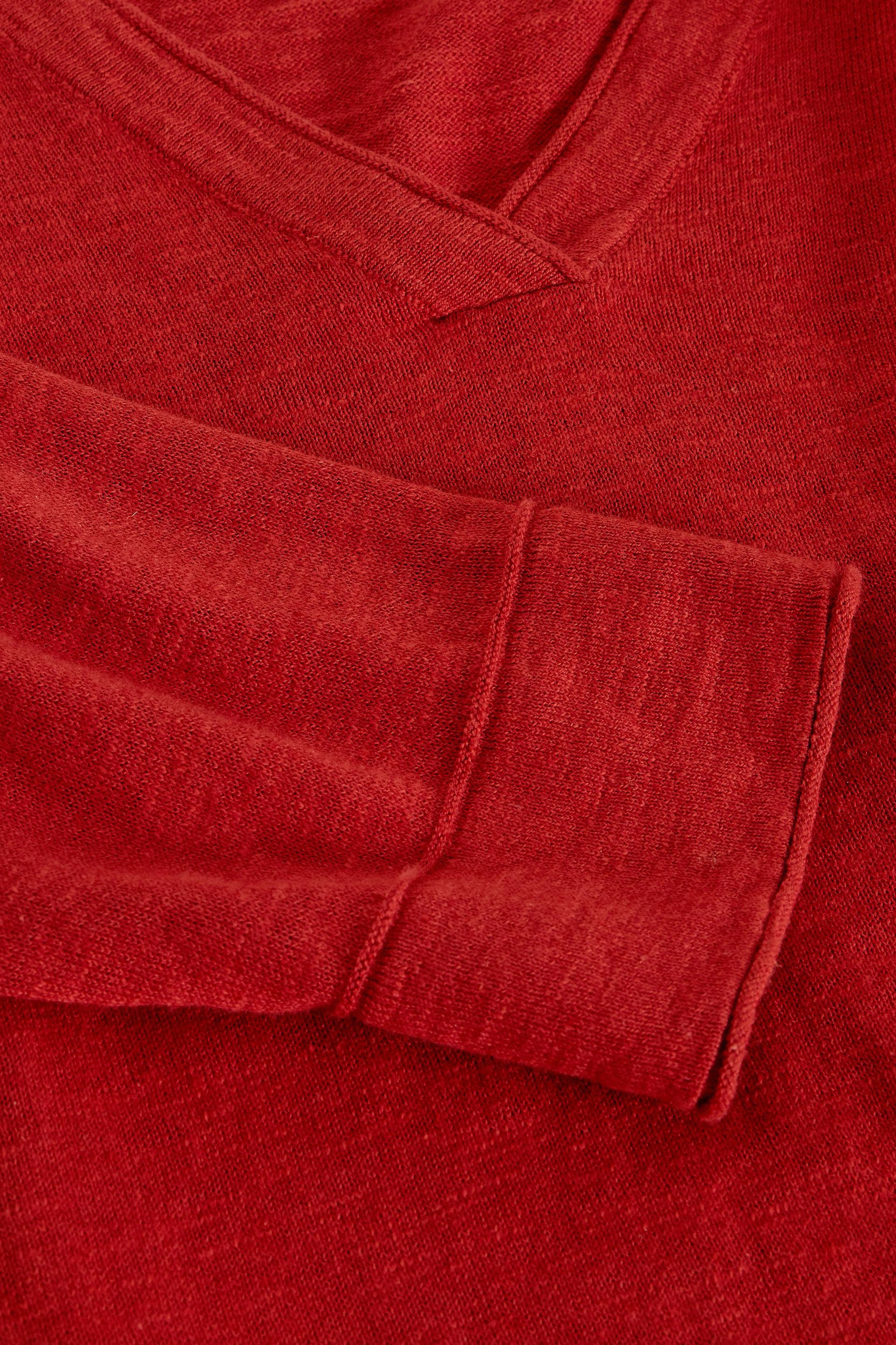 Close-up of a red v-neck sweater made from soft organic cotton with visible fabric texture.