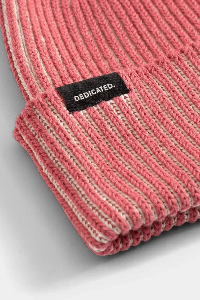 Close-up of a ribbed red cotton beanie with a black Dedicated Clothing brand tag.