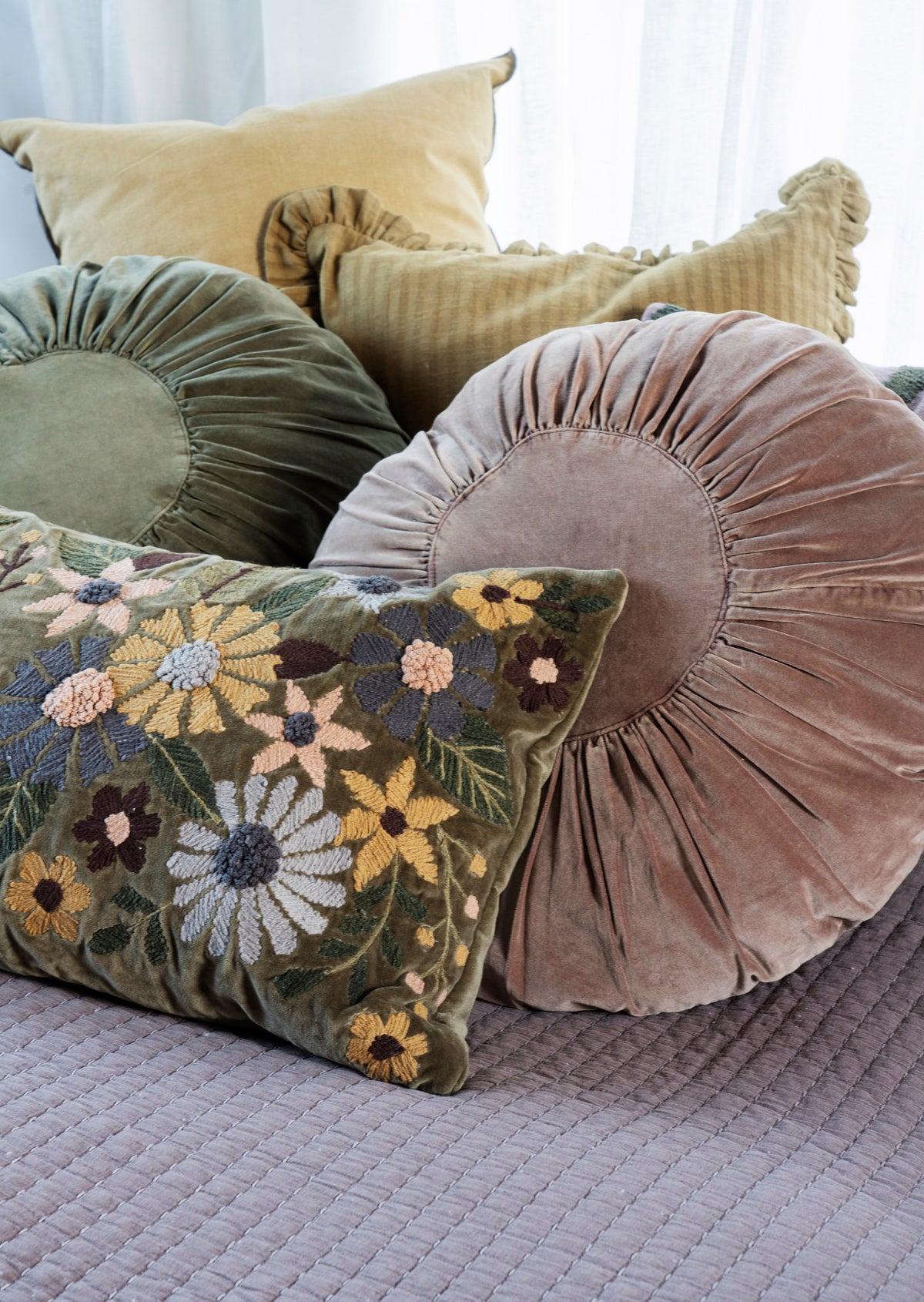 Collection of round velvet cushions and a floral embroidered cotton velvet pillow