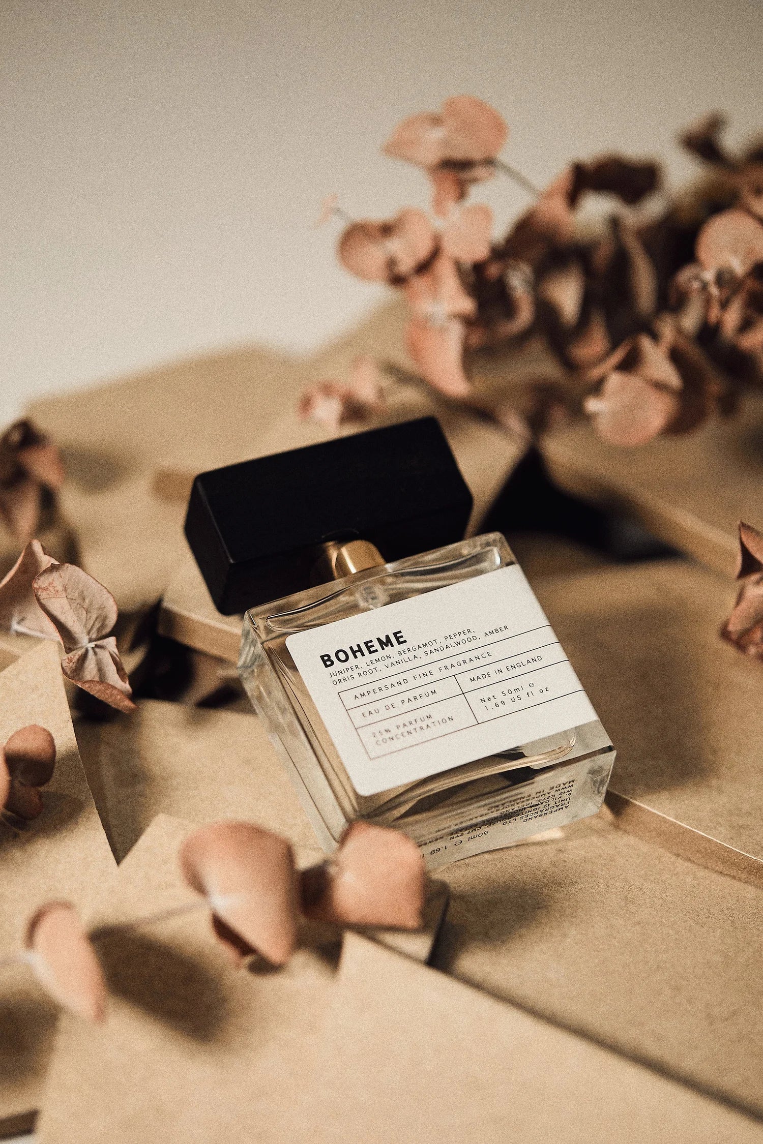 Perfume bottle labeled 'Boheme' on a textured surface with dried flowers.