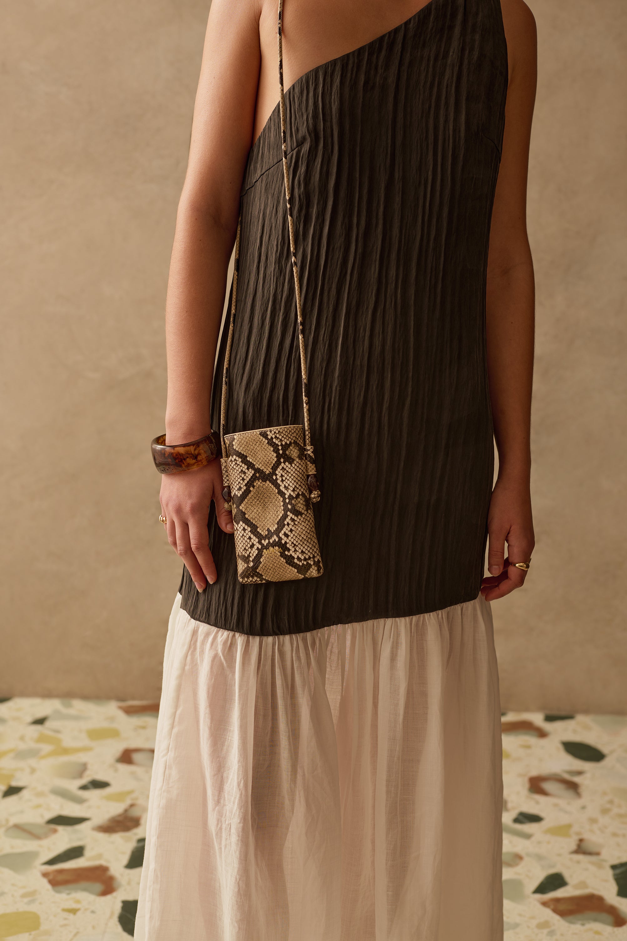 Model wearing a black and white sleeveless maxi dress, with a patterned handbag.