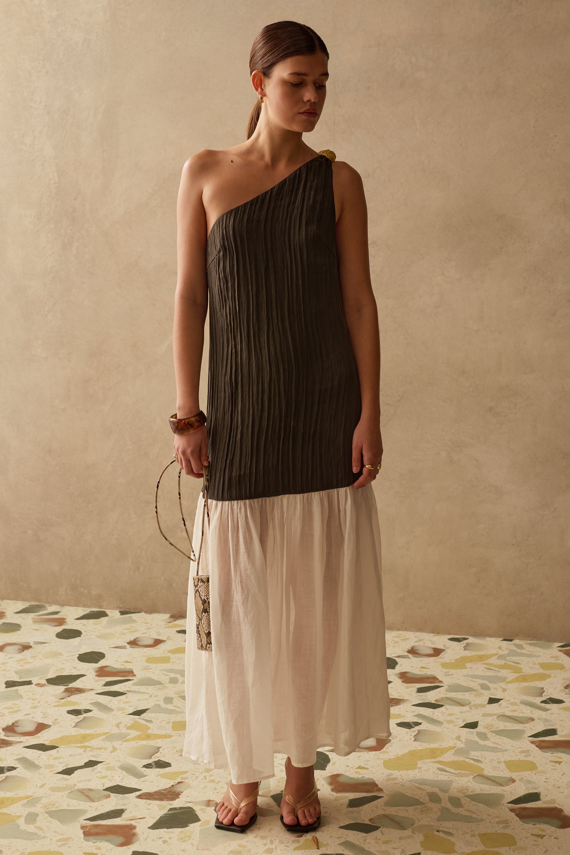Woman wearing a one-shoulder Sancia dress with a plain background