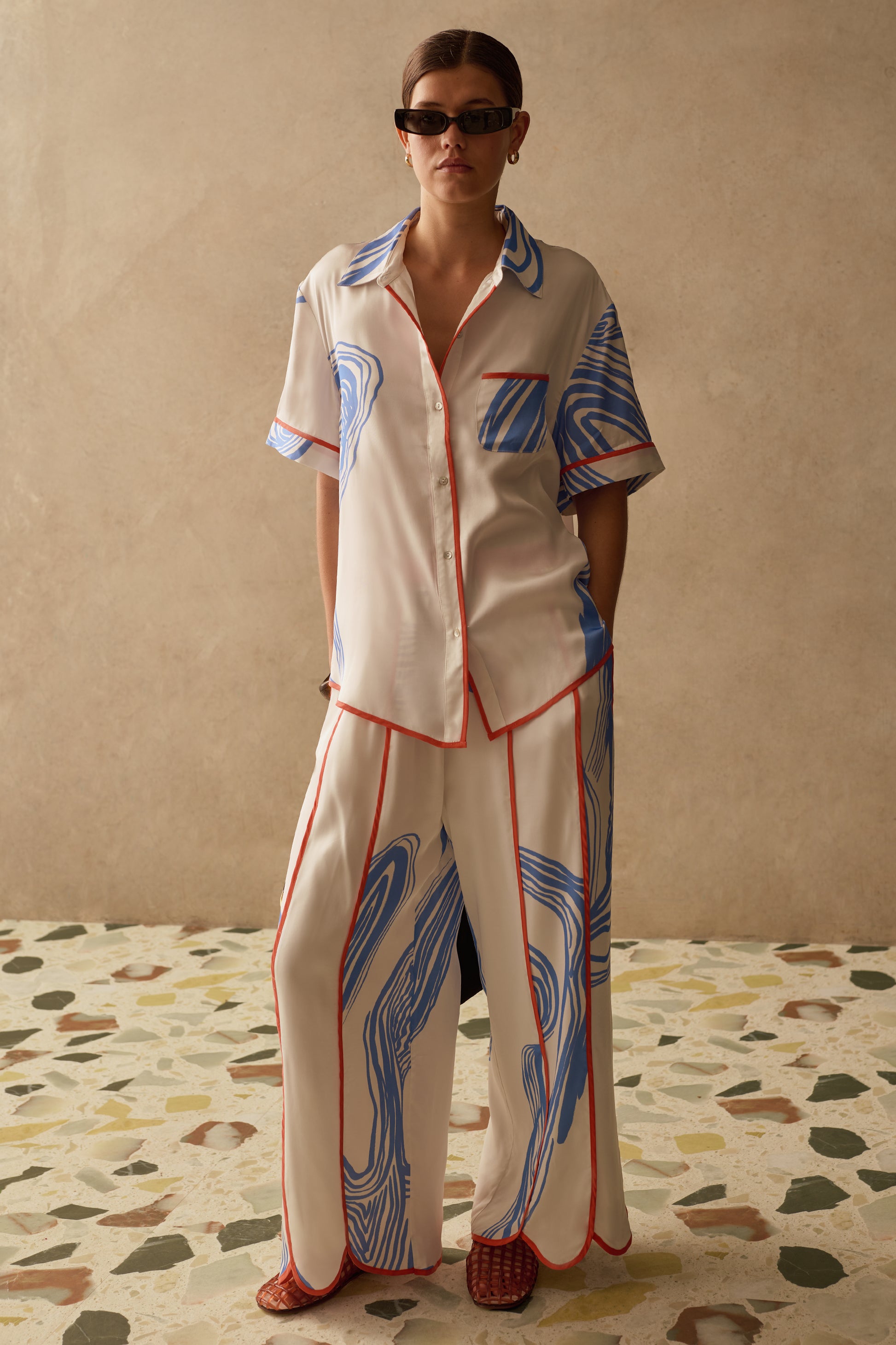 Model wearing Sancia matching two piece shirt and trousers with blue print and orange panelling