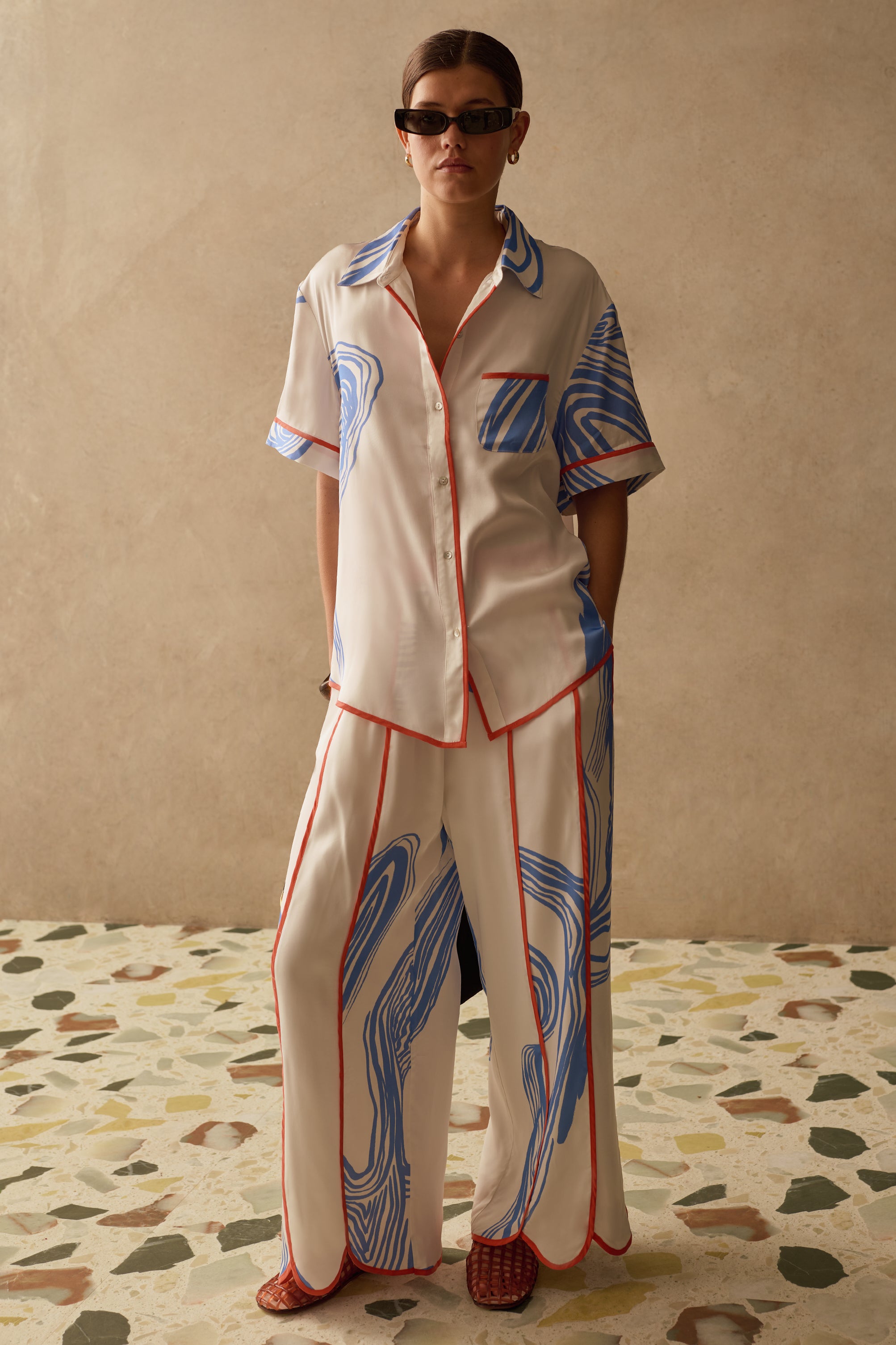 Model wearing Sancia matching two piece shirt and trousers with blue print and orange panelling