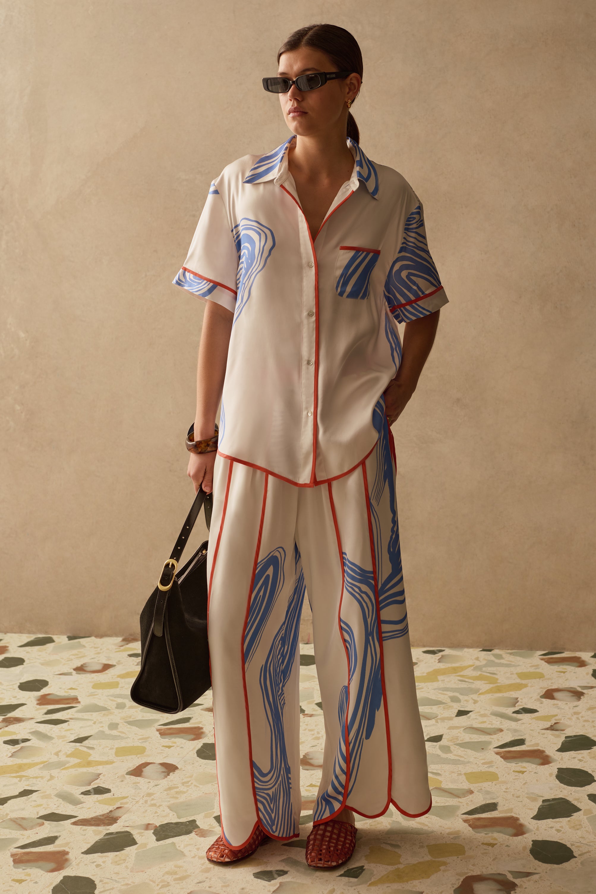 Model wearing matching summer outfit with white printed wide leg trousers and relaxed button down shirt