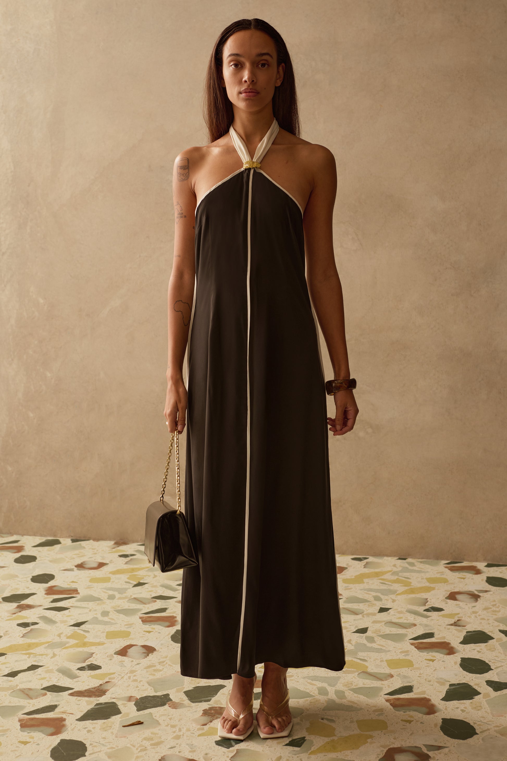 Woman wearing a black halter neck dress with a beige background