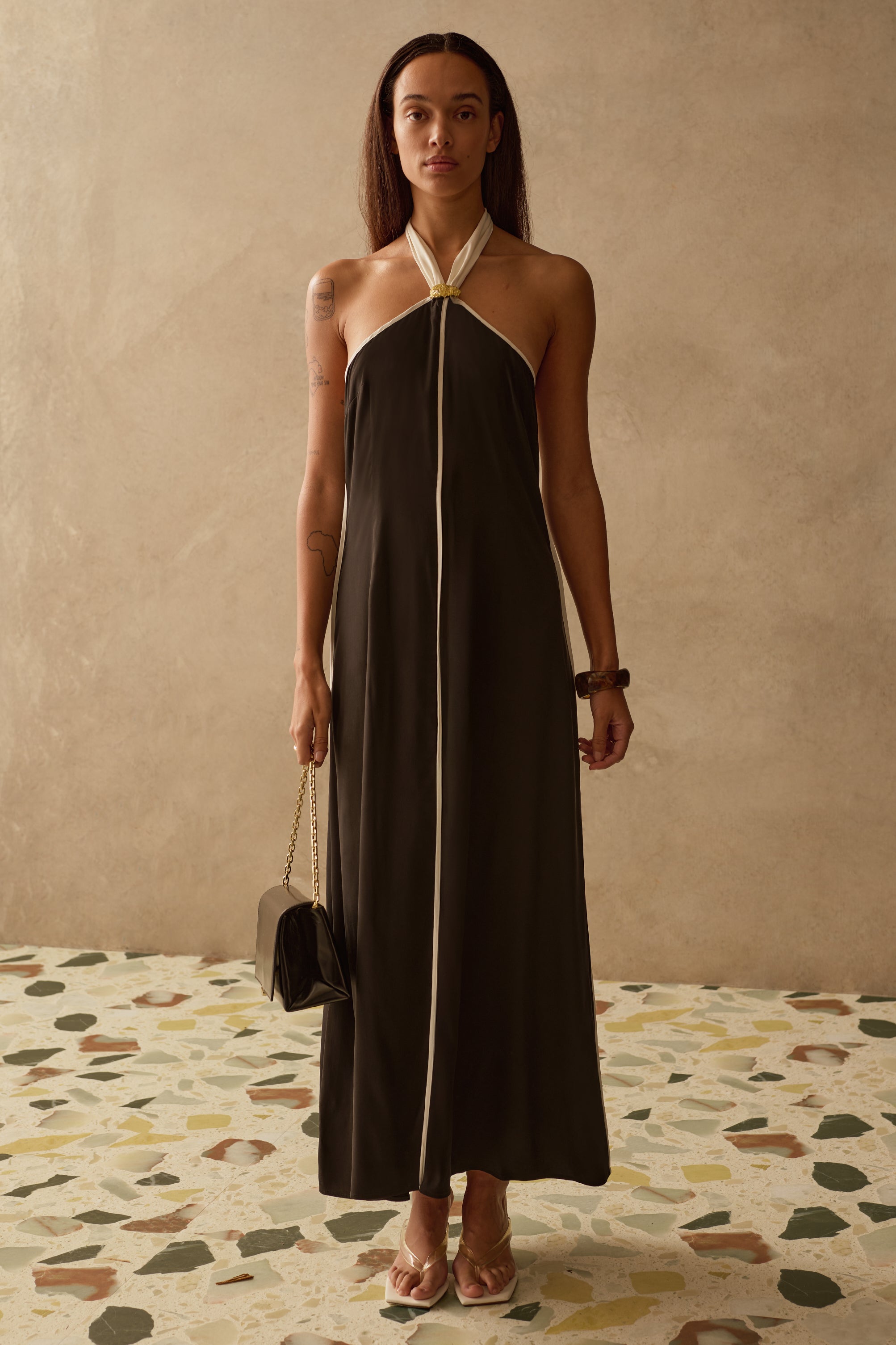 Woman wearing a black halter neck dress with a beige background