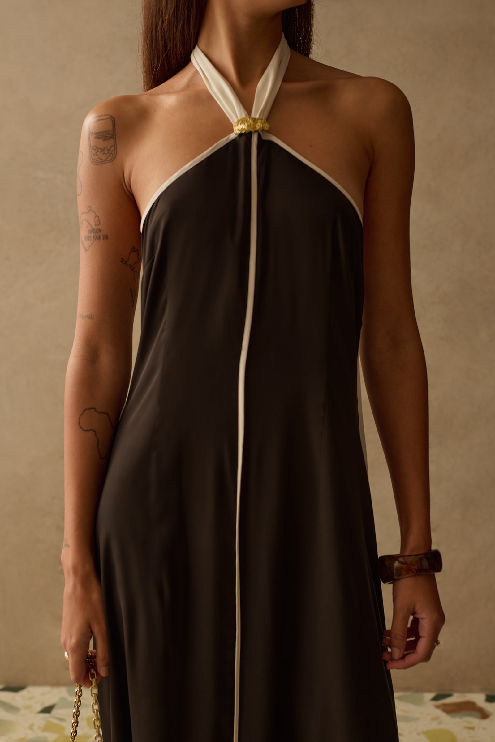 Woman wearing a black and white halter neck dress against a beige background