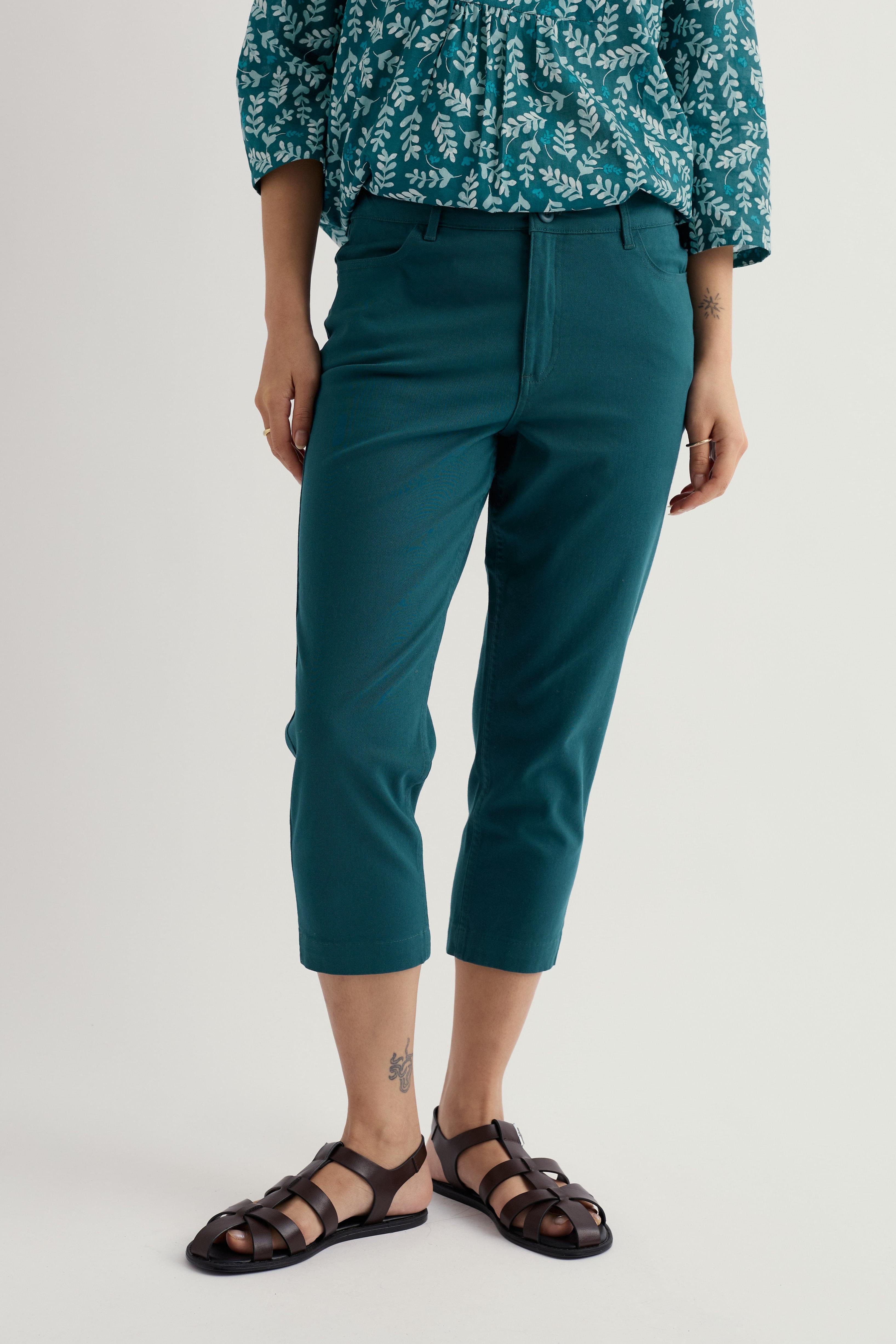 Person wearing teal organic cotton cropped pants and a patterned top on a light gray background