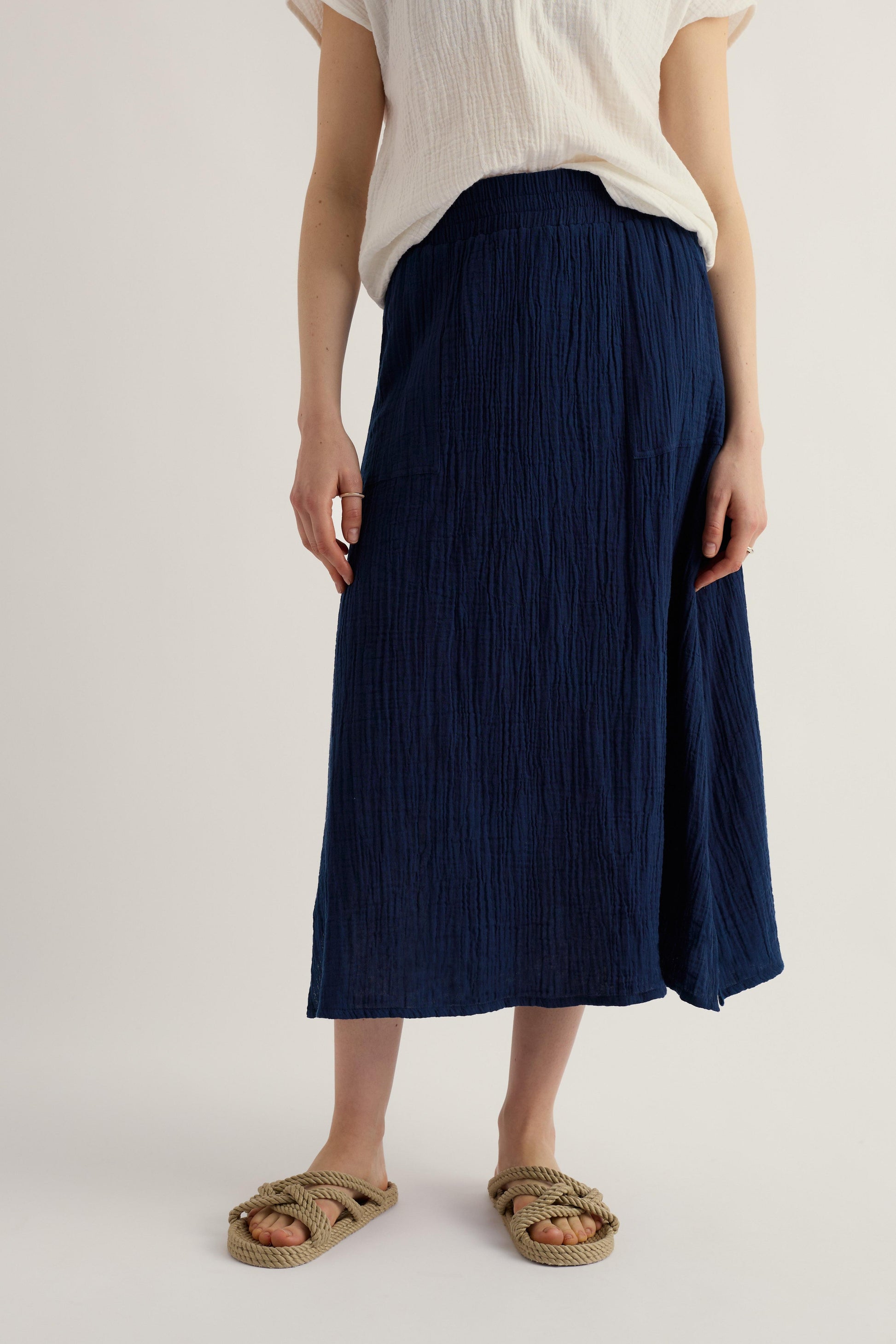 Woman wearing long navy skirt with beige sandels and white blouse