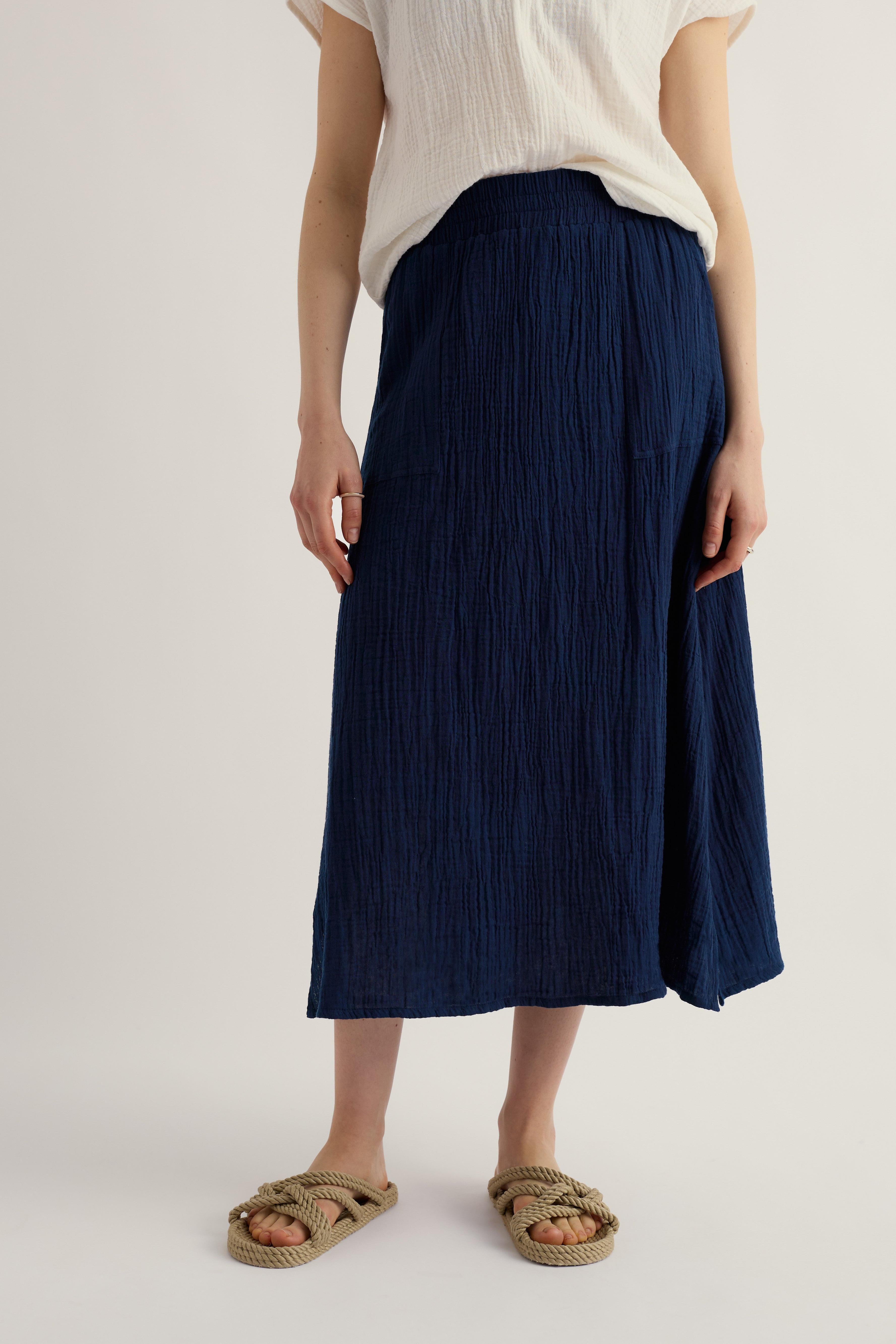 Woman wearing long navy skirt with beige sandels and white blouse