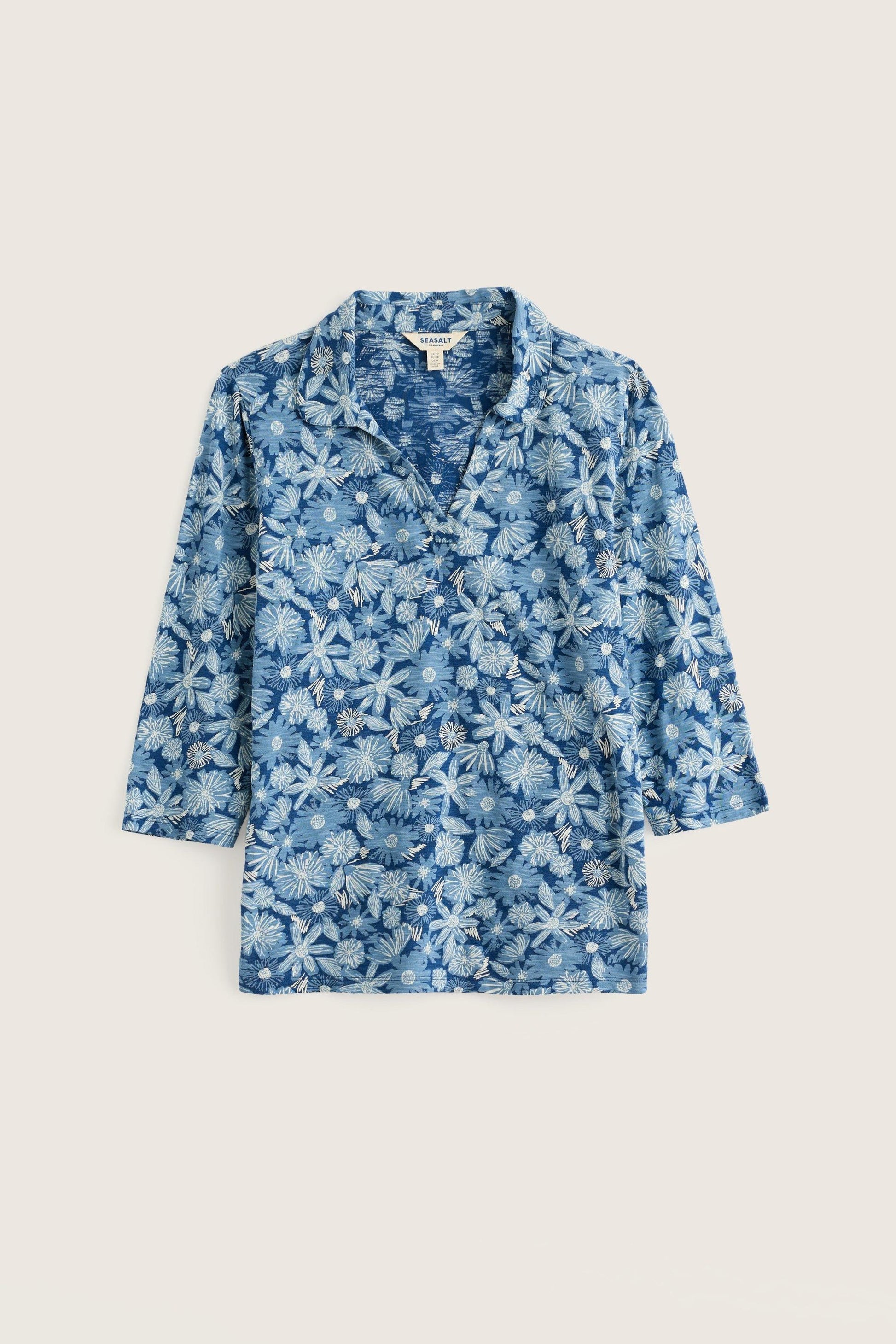 A blue and white floral print long-sleeve shirt with a camp collar, displayed flat against a light beige background.