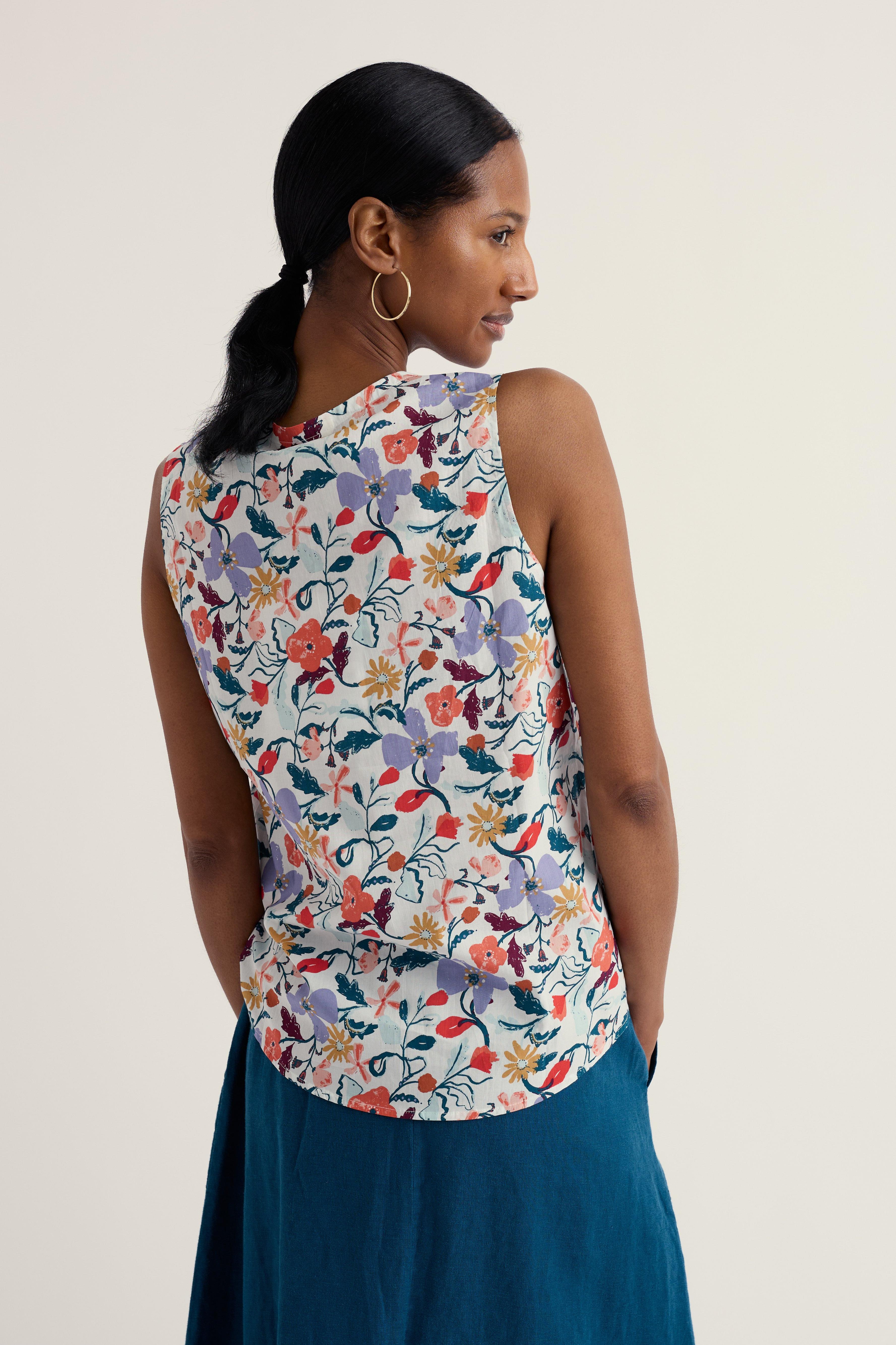 Woman wearing a sleeveless floral top with a plain background