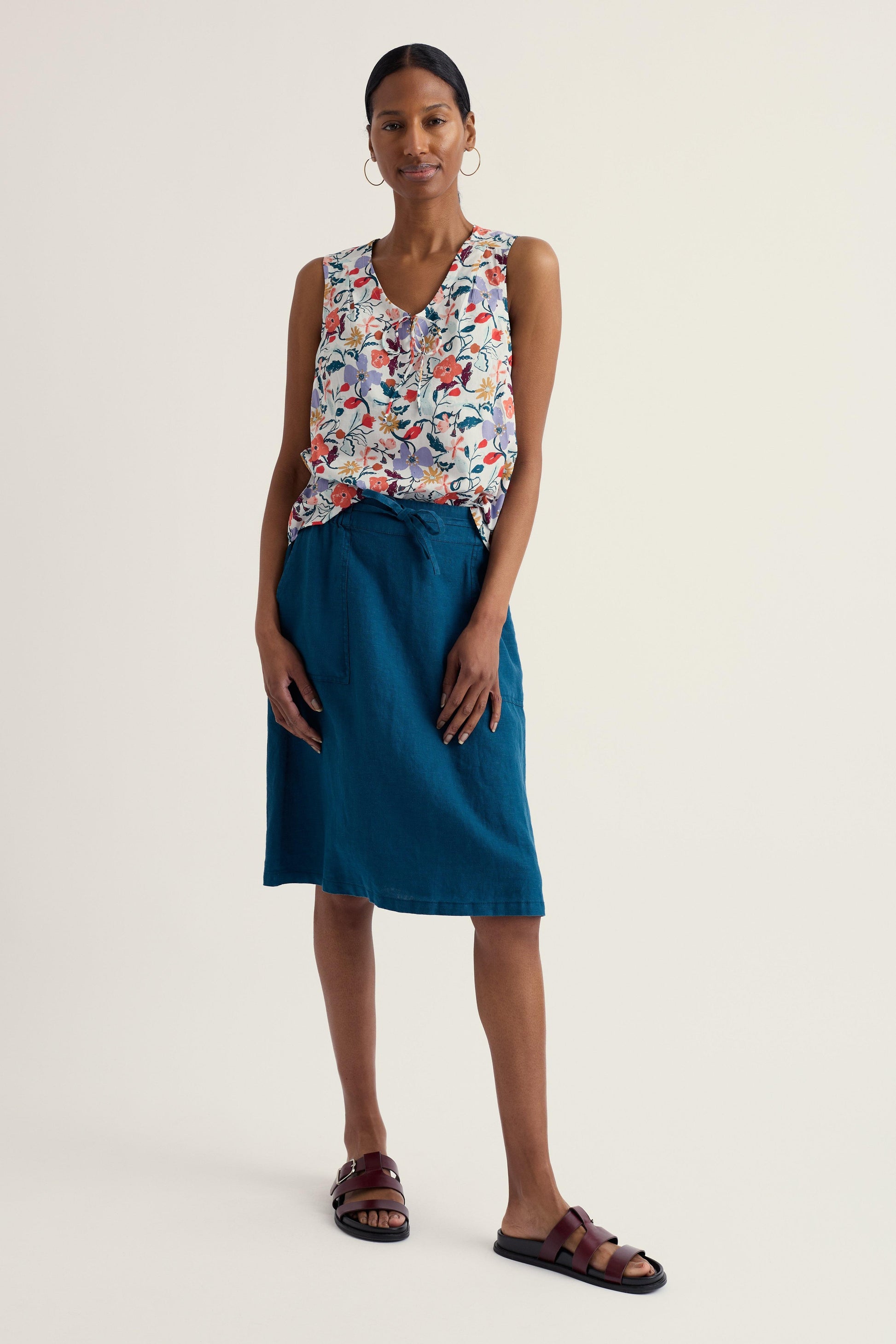 Woman wearing a floral top and blue skirt on a white background