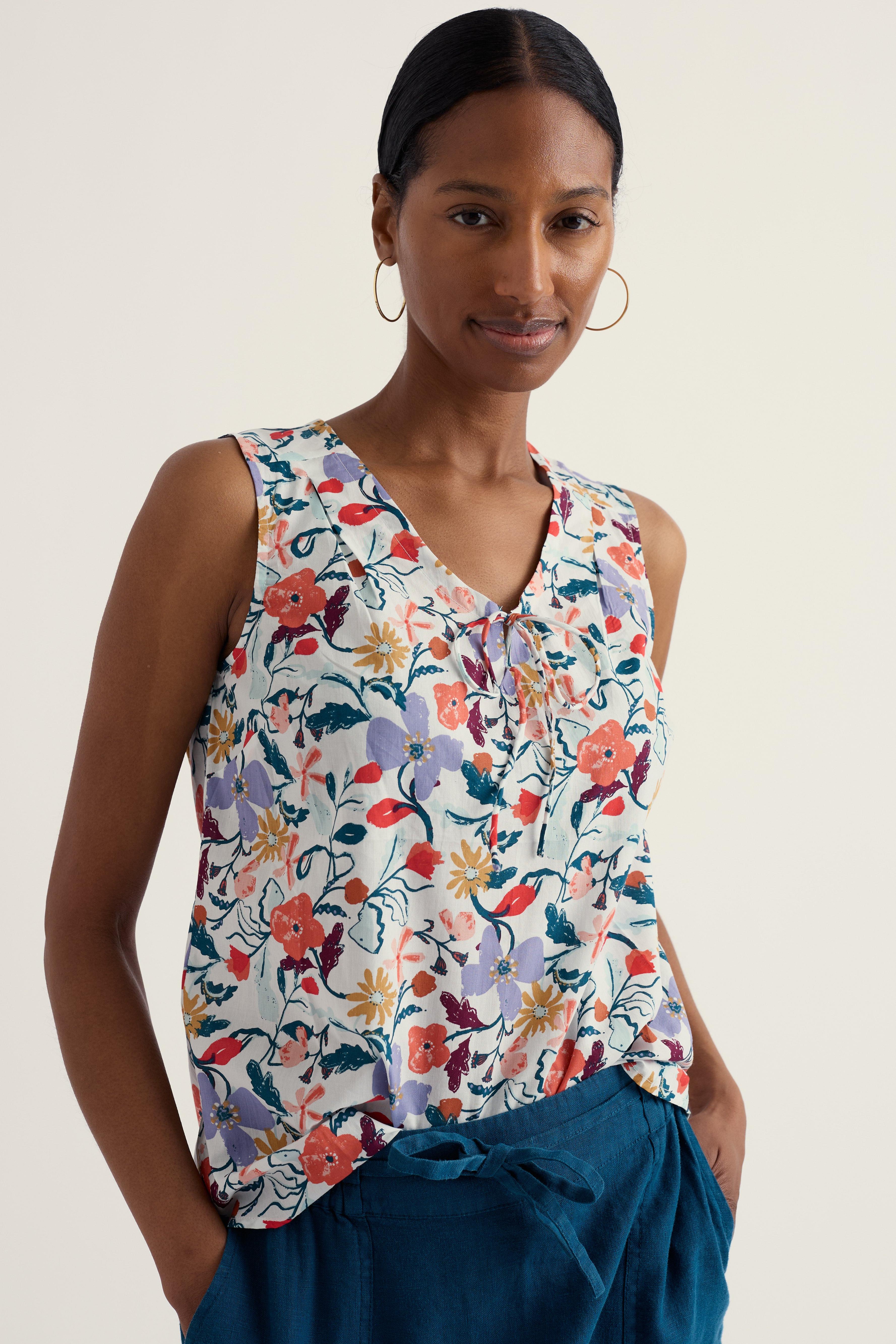 Woman wearing a sleeveless floral top with a neutral background