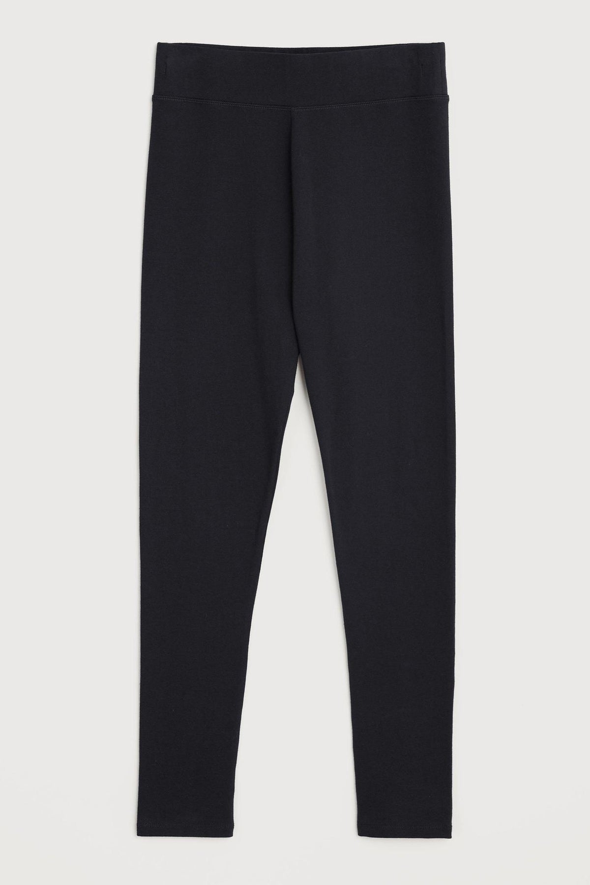 A pair of plain black women's leggings made from organic cotton against a neutral background.